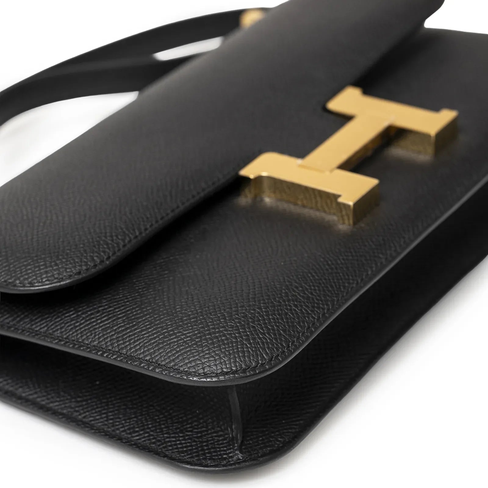 Close-up angled shot of Hermès Constance Elan Black Epsom Gold Hardware showing textured leather and gold clasp details