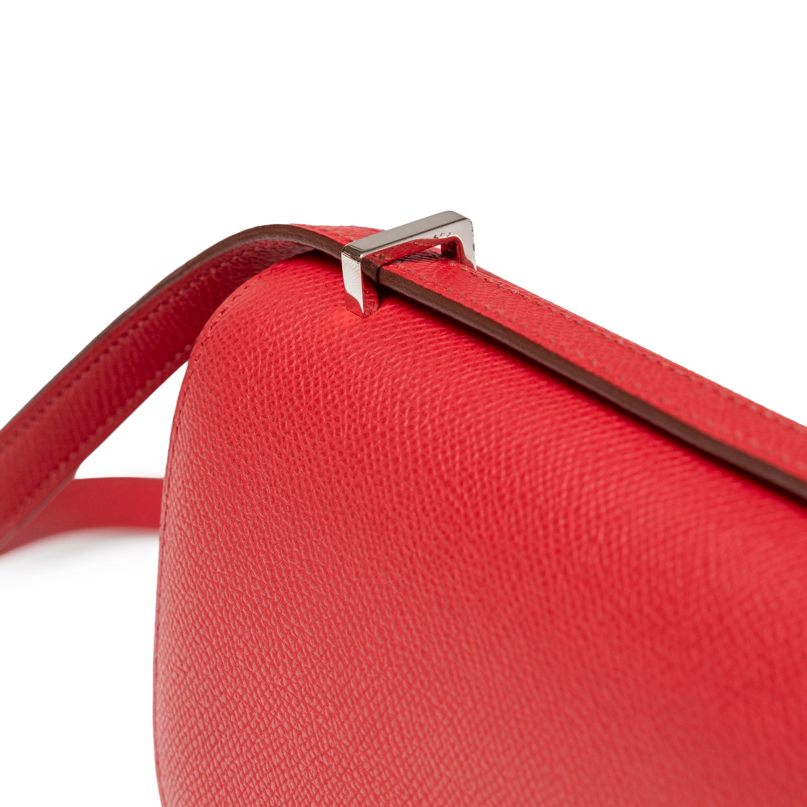 Top corner close-up of Hermès Constance Elan Rouge Epsom Palladium Hardware showing strap attachment detail and textured leather