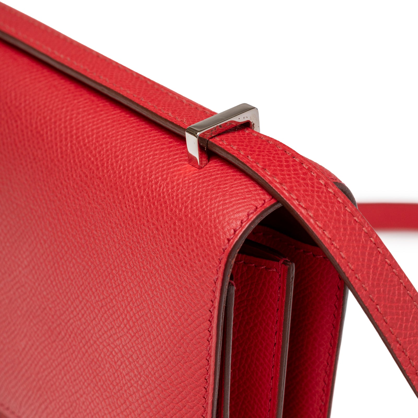 Close-up of side strap attachment and textured red leather on Hermès Constance Elan Rouge Epsom Palladium Hardware