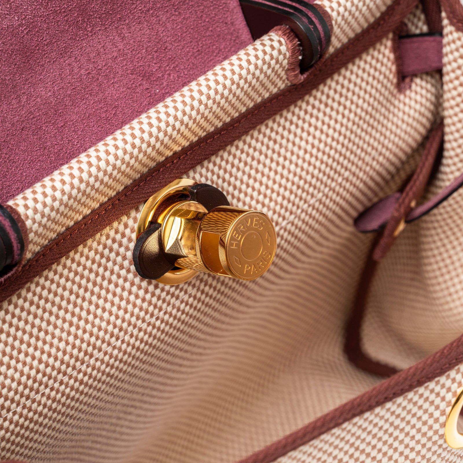 Close-up of gold-toned lock hardware and maroon leather trim on Hermès Herbag Zip PM 31 Ecru and Beige Toile H Ebene Hunter Gold Hardware