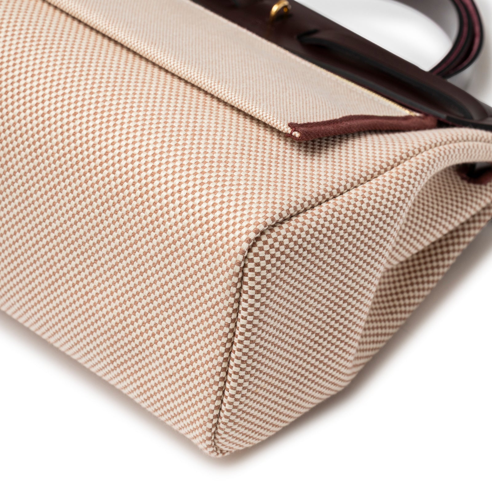 Close-up of textured woven canvas bottom corner and leather trim on Hermès Herbag Zip PM 31 Ecru and Beige Toile H Ebene Hunter Gold Hardware
