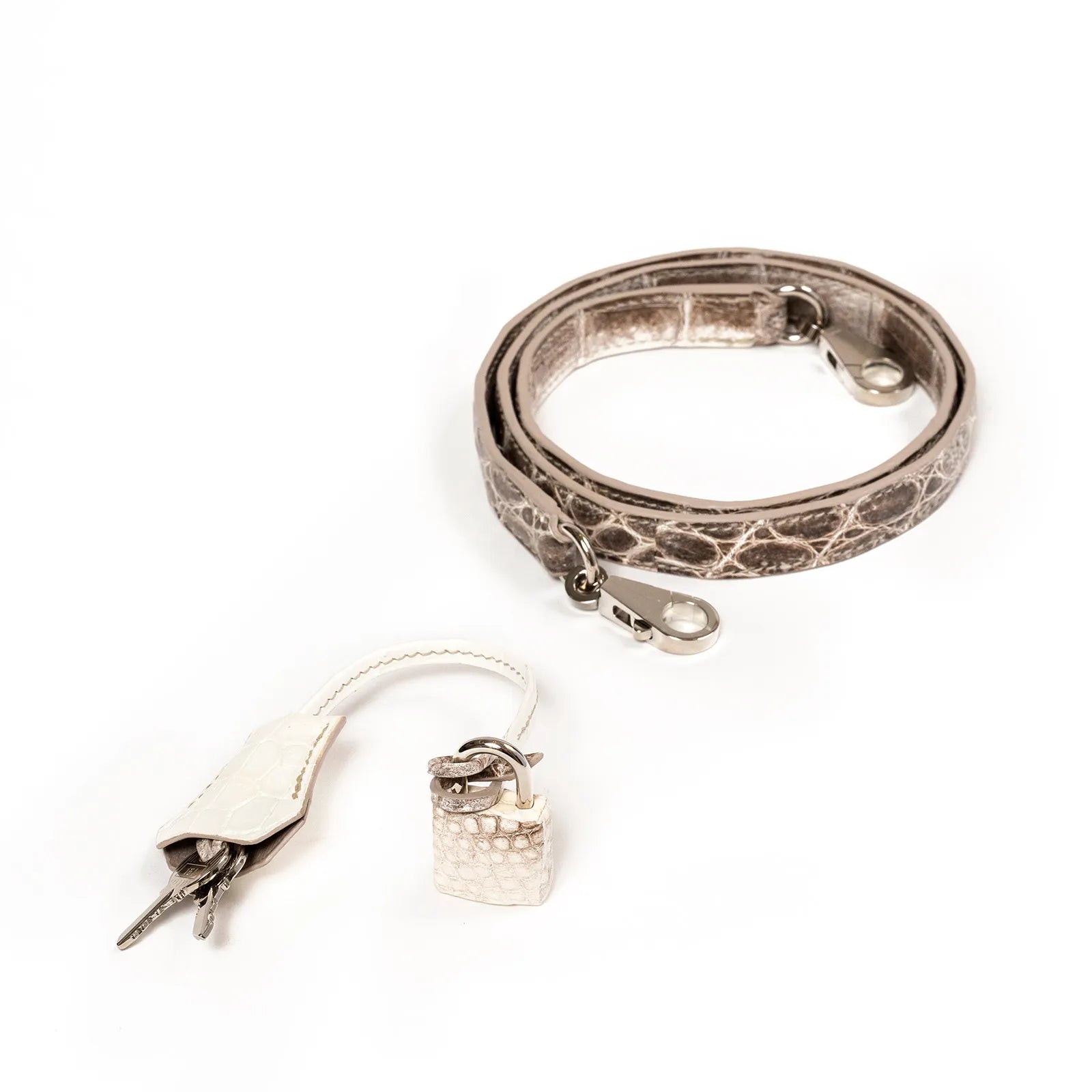 Rolled beige textured strap with metal clasps, accompanied by key and lock.
