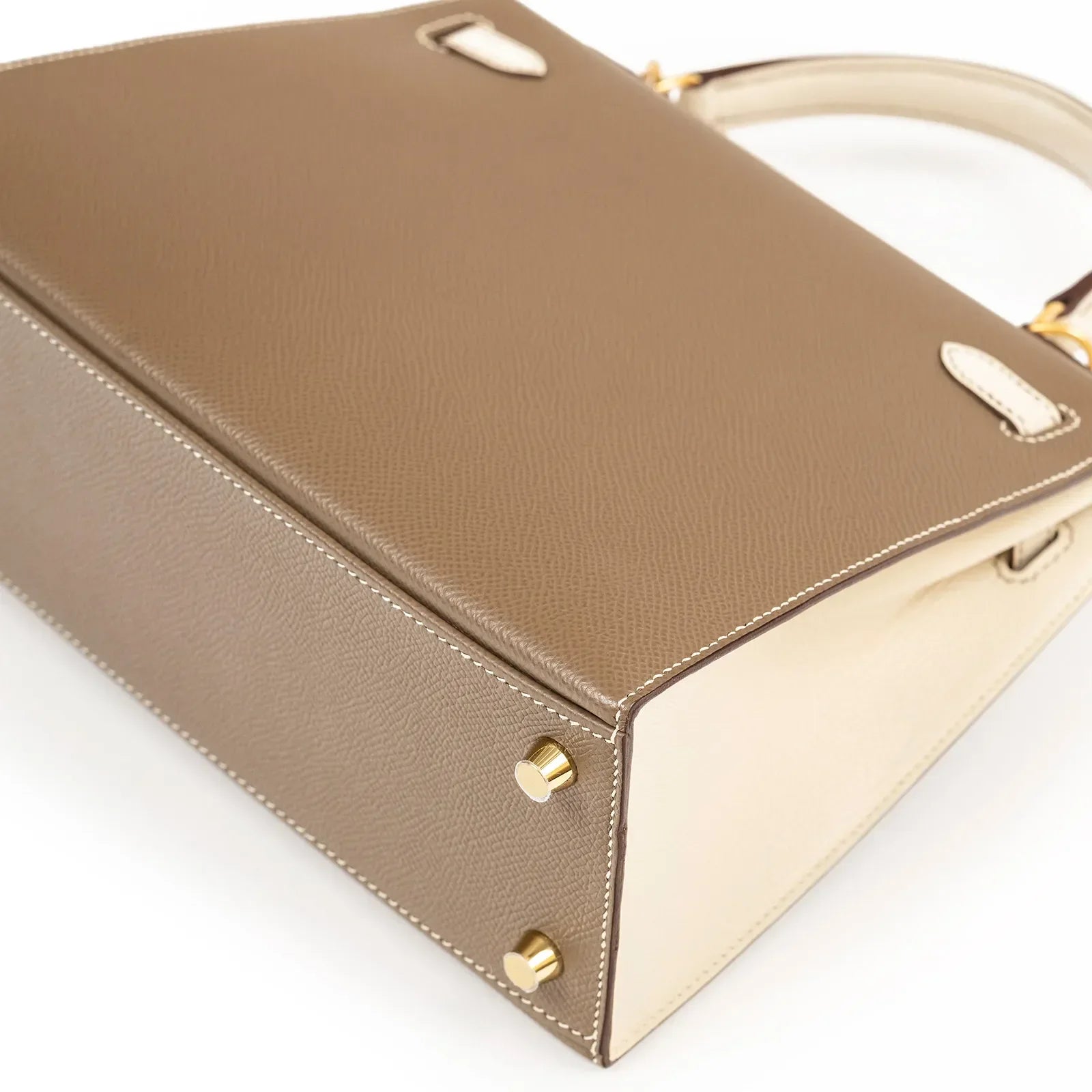 Close-up bottom view of Hermès Horseshoe Kelly 25 Sellier Etoupe/Craie Epsom Brushed Gold Hardware showing leather texture and gold studs