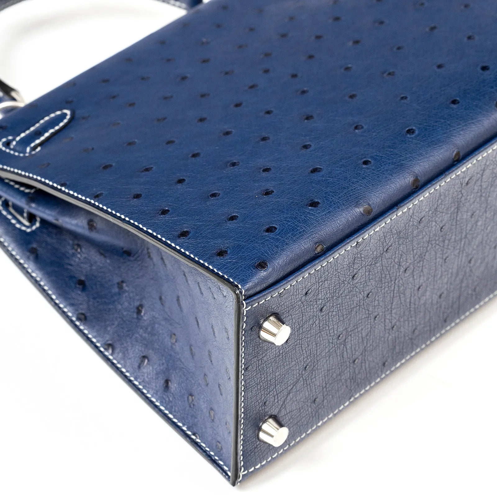 Close-up angled view of Hermès Horseshoe Kelly 25 Sellier Ostrich Blue Iris Gris with Palladium Hardware feet and stitching details
