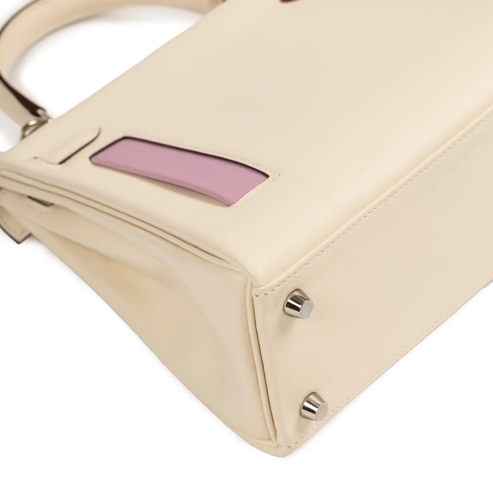 Close-up angled shot of Hermès Kelly 25 in nata leather showing purple detail and palladium hardware feet