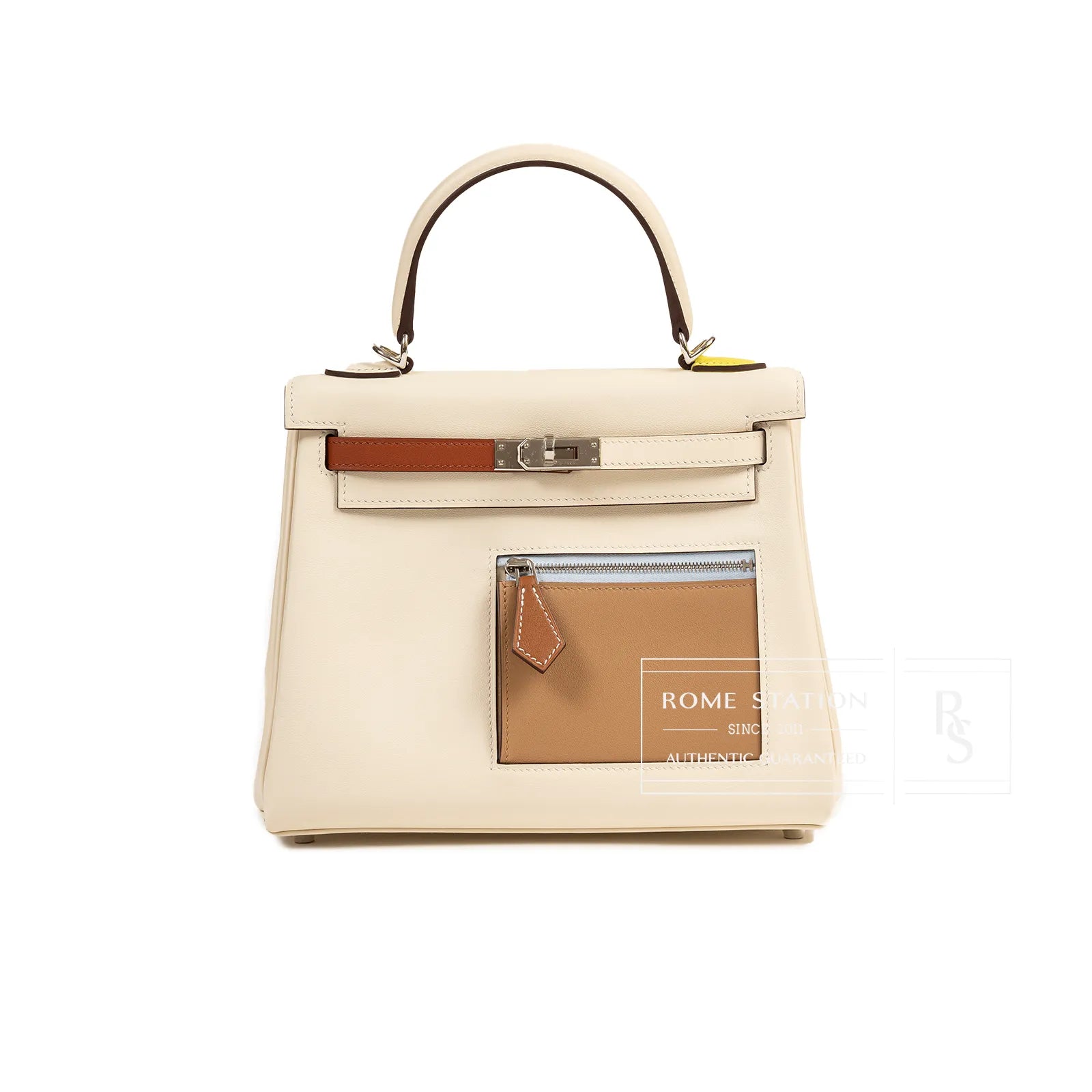 Front view of cream Hermès Kelly 25 with brown front pocket and silver hardware on white background