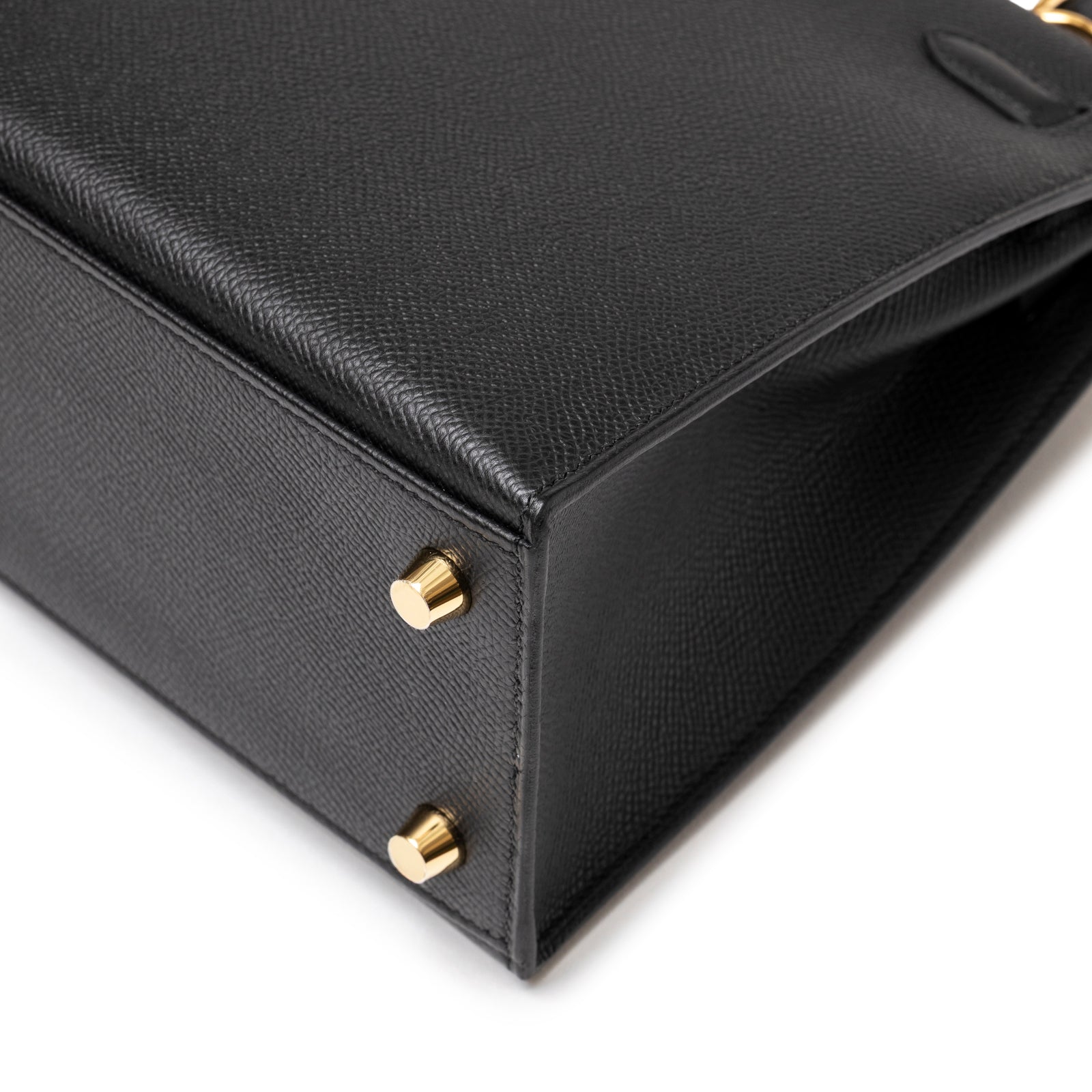 Close-up of bottom corner showing textured black leather and gold feet on Hermès Kelly 25 Sellier Black Epsom Gold Hardware handbag