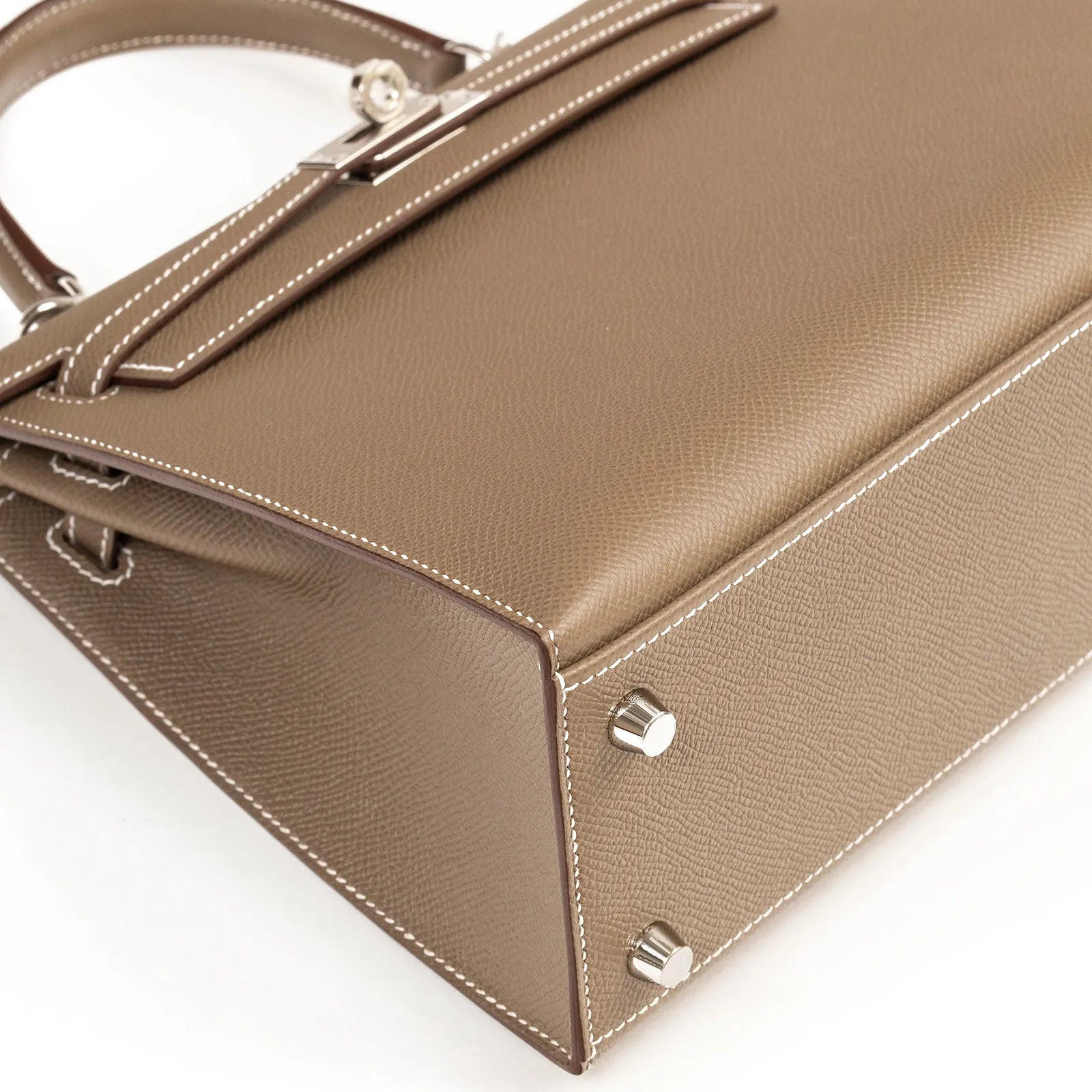 Hermès Kelly 25 Sellier Etoupe Epsom Palladium Hardware handbag and detailed stitching on a white background