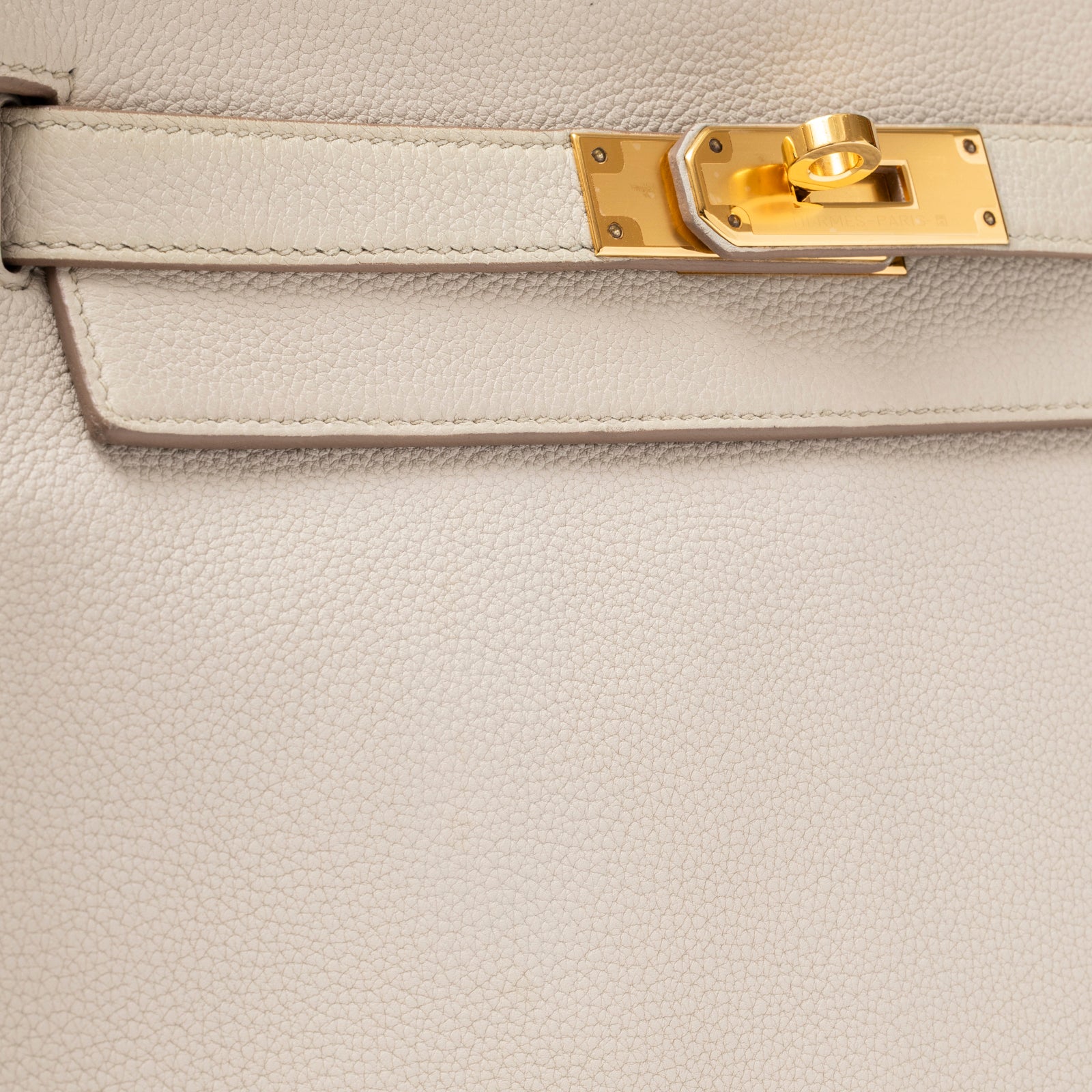 Close-up of textured beige leather and gold turn-lock clasp on Hermès Kelly 28 Retourne Beton Togo Gold Hardware