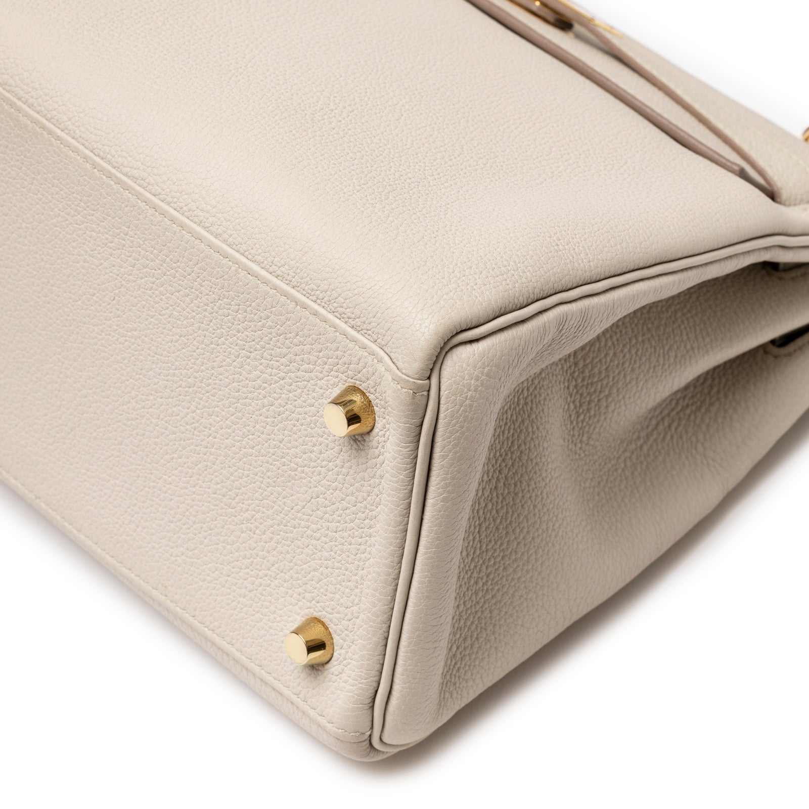 Close-up of bottom corner on Hermès Kelly 28 Retourne Beton Togo Gold Hardware showing leather grain and gold feet detail
