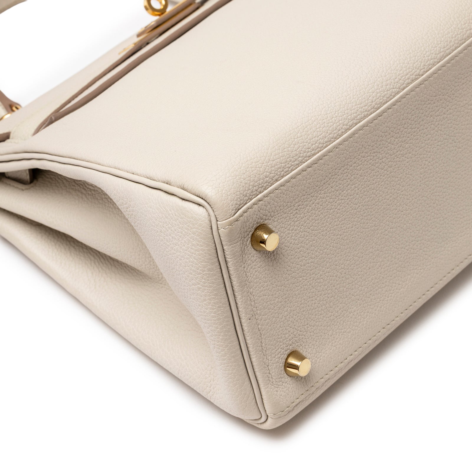 Close-up of bottom corner on Hermès Kelly 28 Retourne Beton Togo Gold Hardware showing textured leather and gold feet
