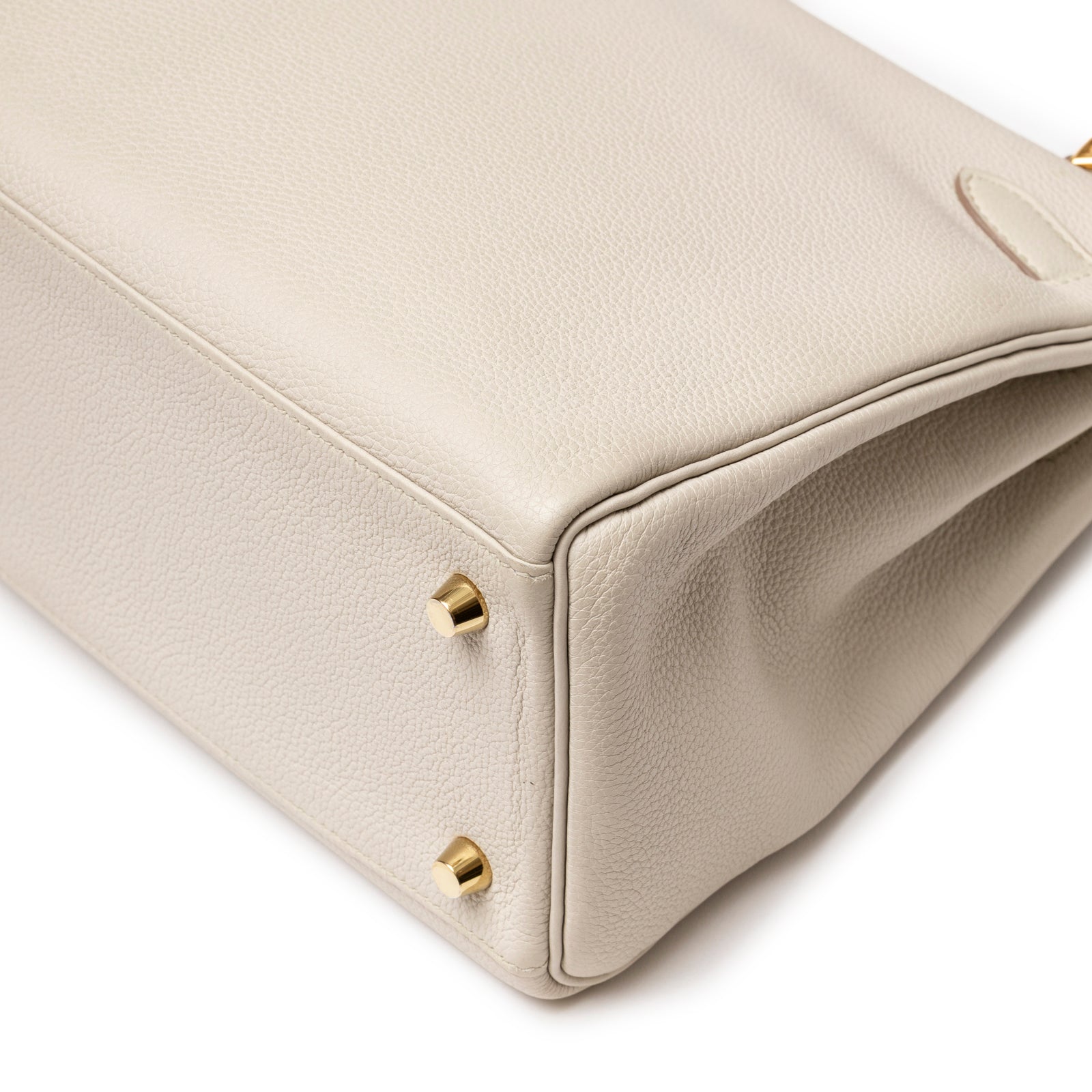Close-up back corner of Hermès Kelly 28 Retourne Beton Togo Gold Hardware showing pebbled leather and gold feet side angle