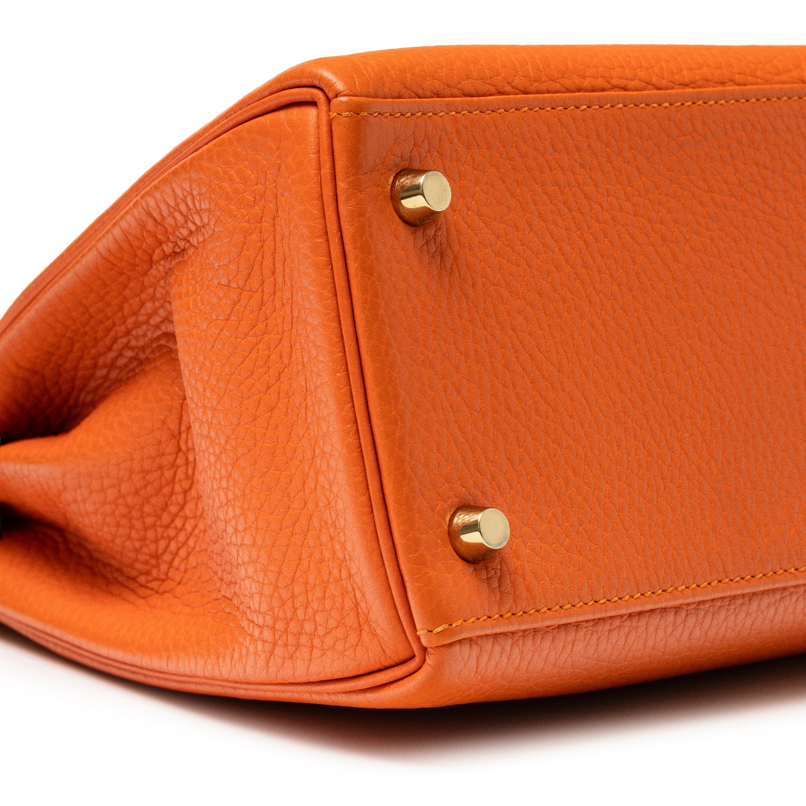 Close-up bottom view of Hermès Kelly 28 Retourne Orange Clemence Gold Hardware showing leather texture and metal feet