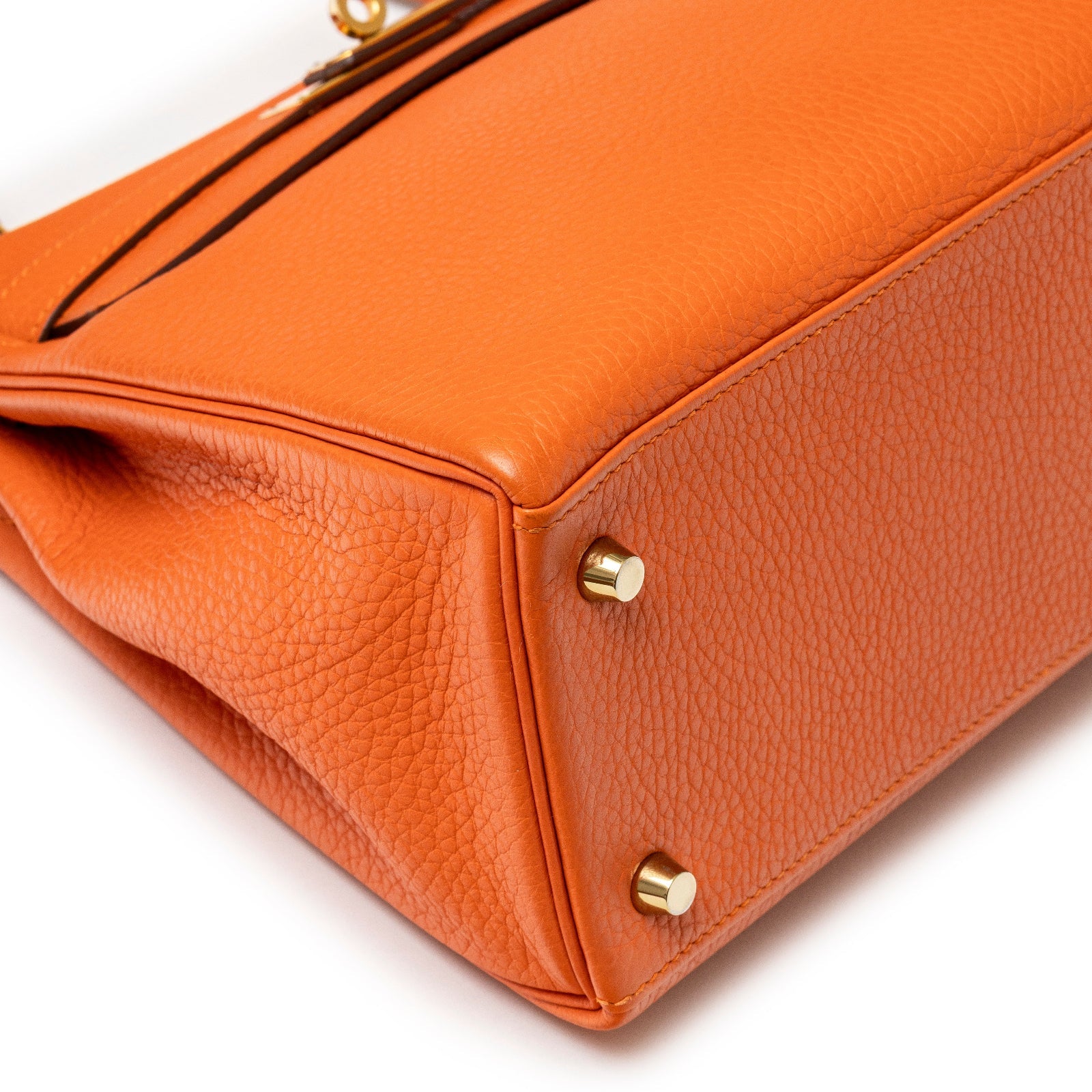Close-up bottom corner view of Hermès Kelly 28 Retourne Orange Clemence Gold Hardware handbag detailing