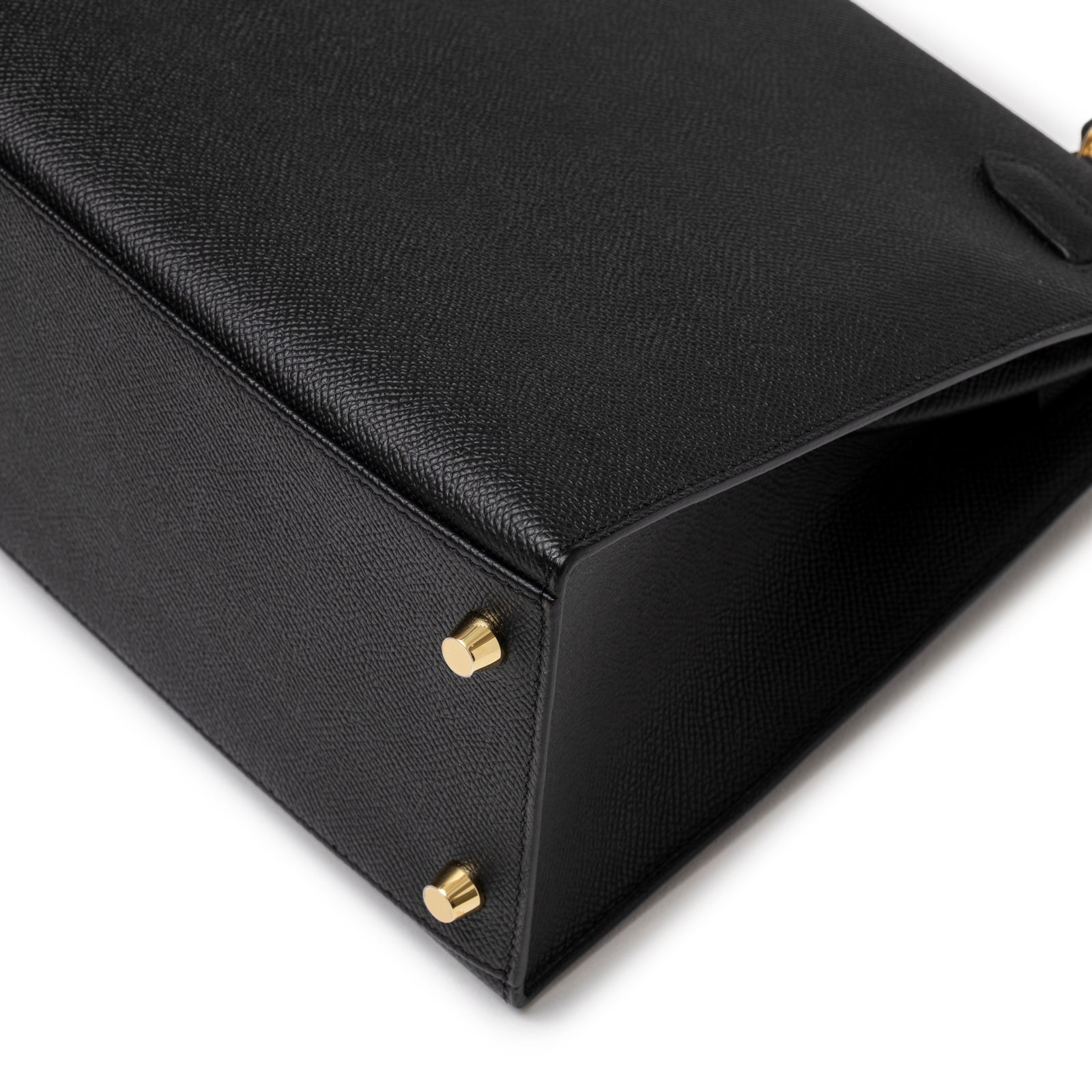 Close-up of base corner on Hermès Kelly 28 Sellier Black Epsom Gold Hardware showing grainy leather and gold feet details
