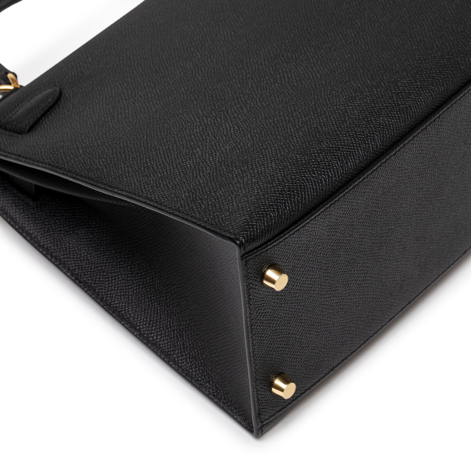 Close-up of base corner on Hermès Kelly 28 Sellier Black Epsom Gold Hardware showing textured leather and gold studs