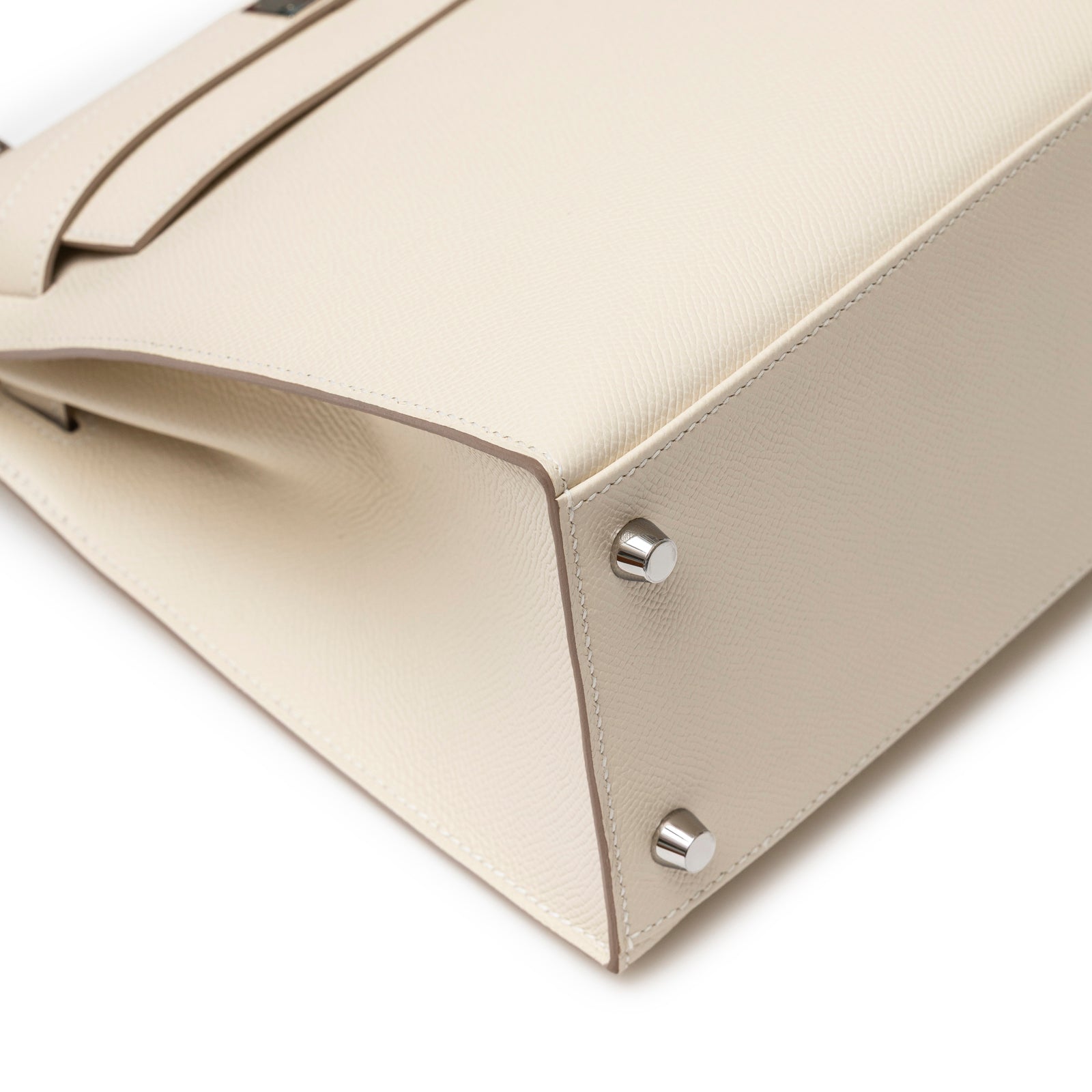 Close-up of bottom corner and silver feet on Hermès Kelly 28 Sellier Craie Epsom Palladium Hardware handbag