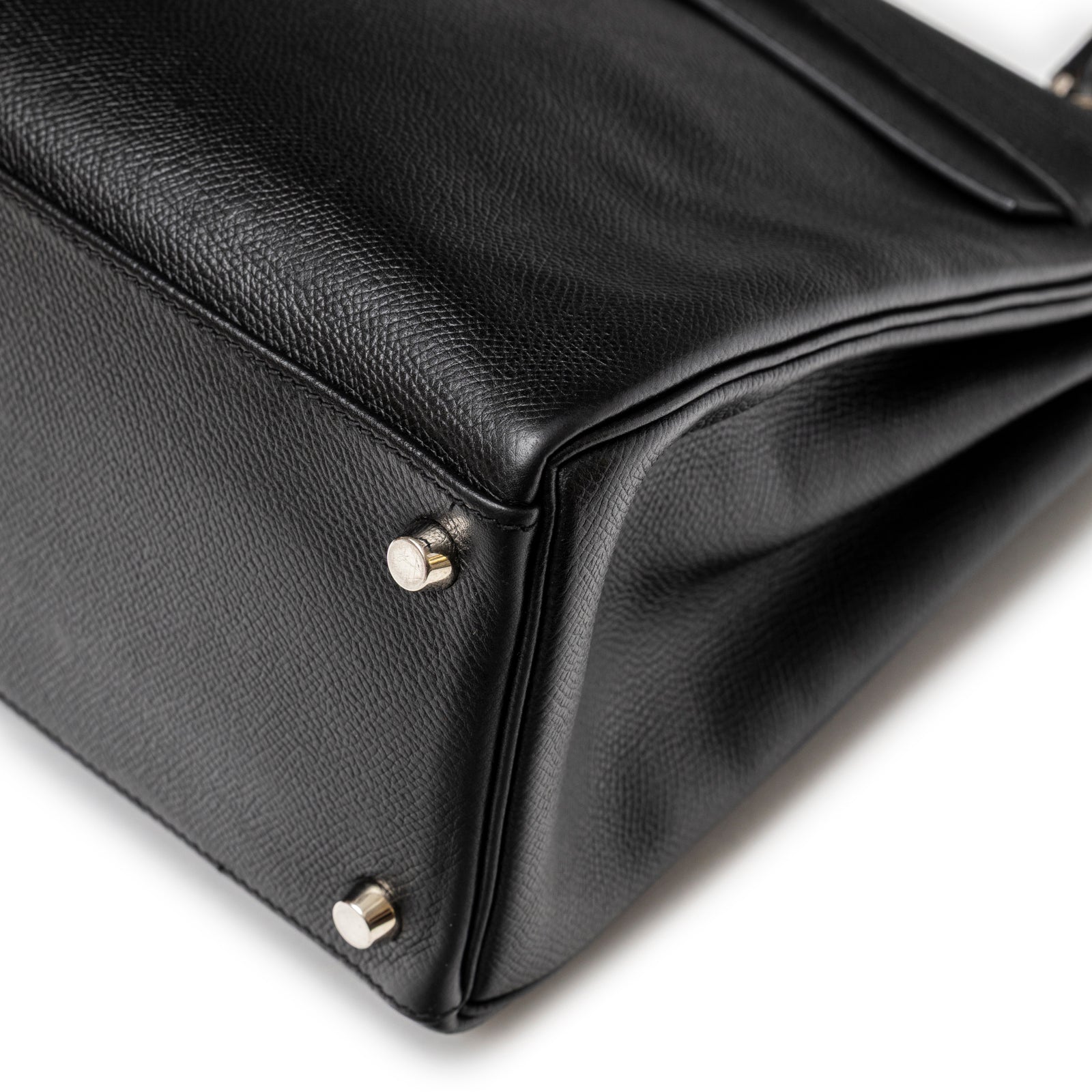 Close-up of black textured leather corner and palladium metal feet on Hermès Kelly 32 Black Epsom Palladium Hardware bag