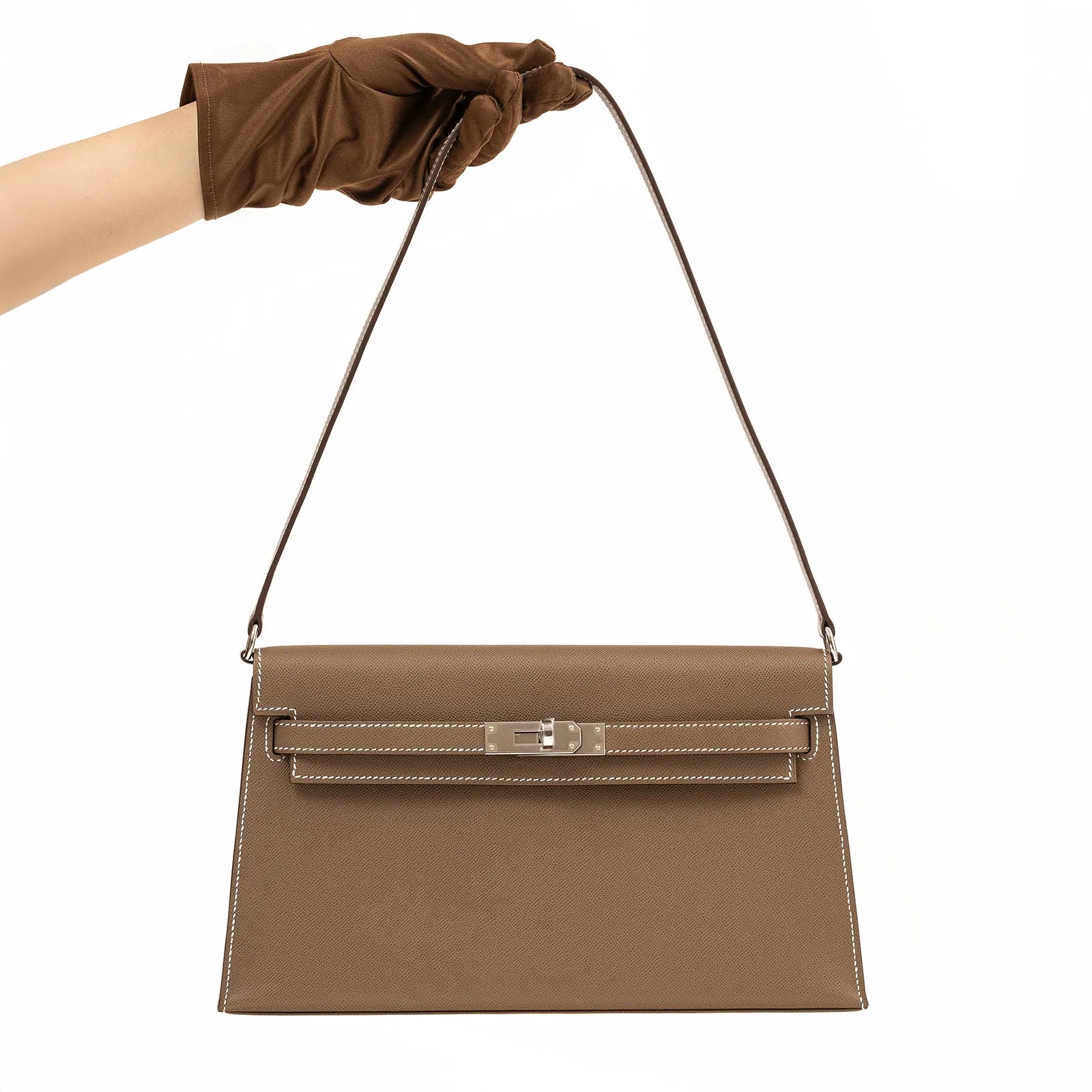 Front view of Hermès Kelly Elan Etoupe Madame Palladium Hardware held by gloved hand showing smooth leather and clasp details