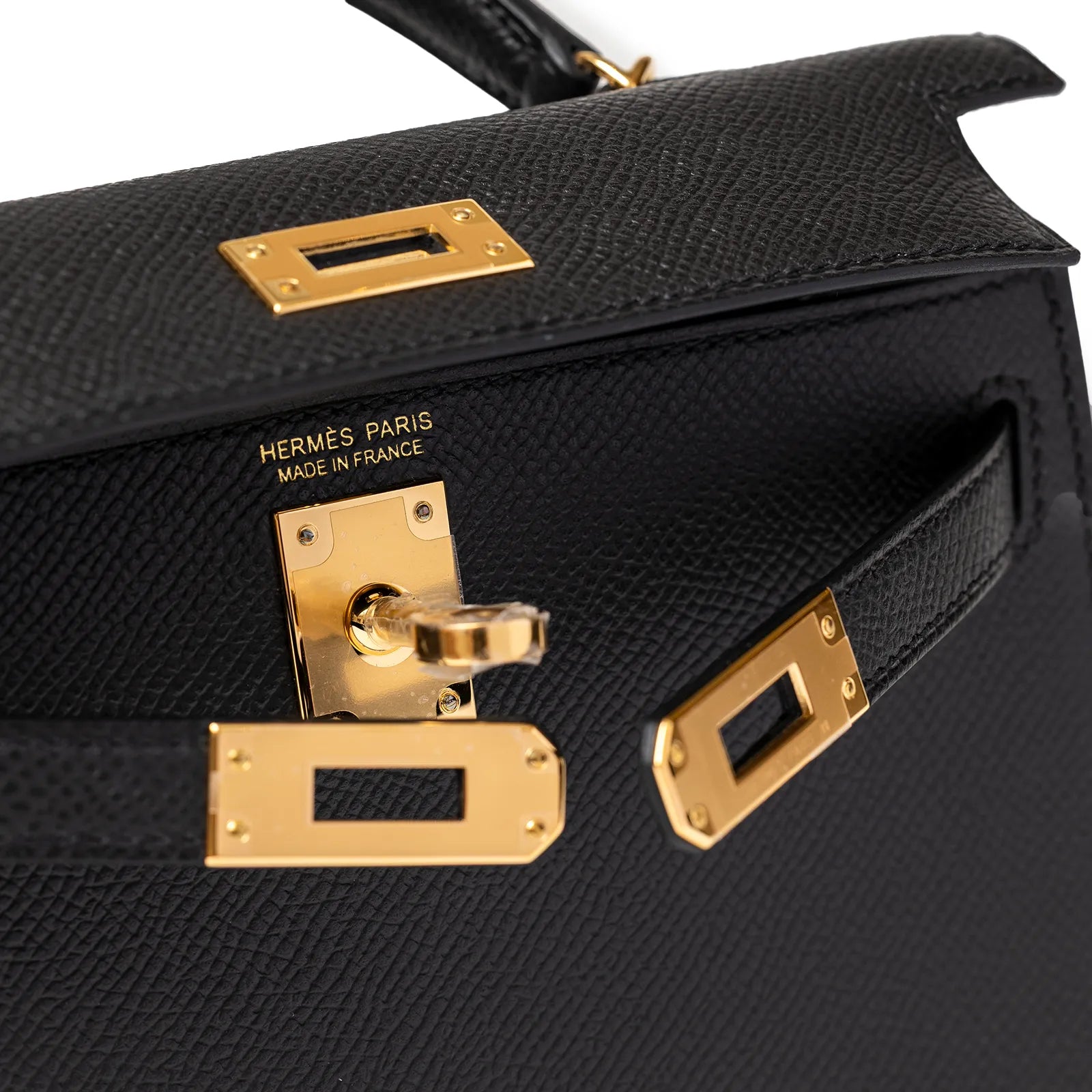 Close-up of black leather bag with gold hardware and visible stitching details.