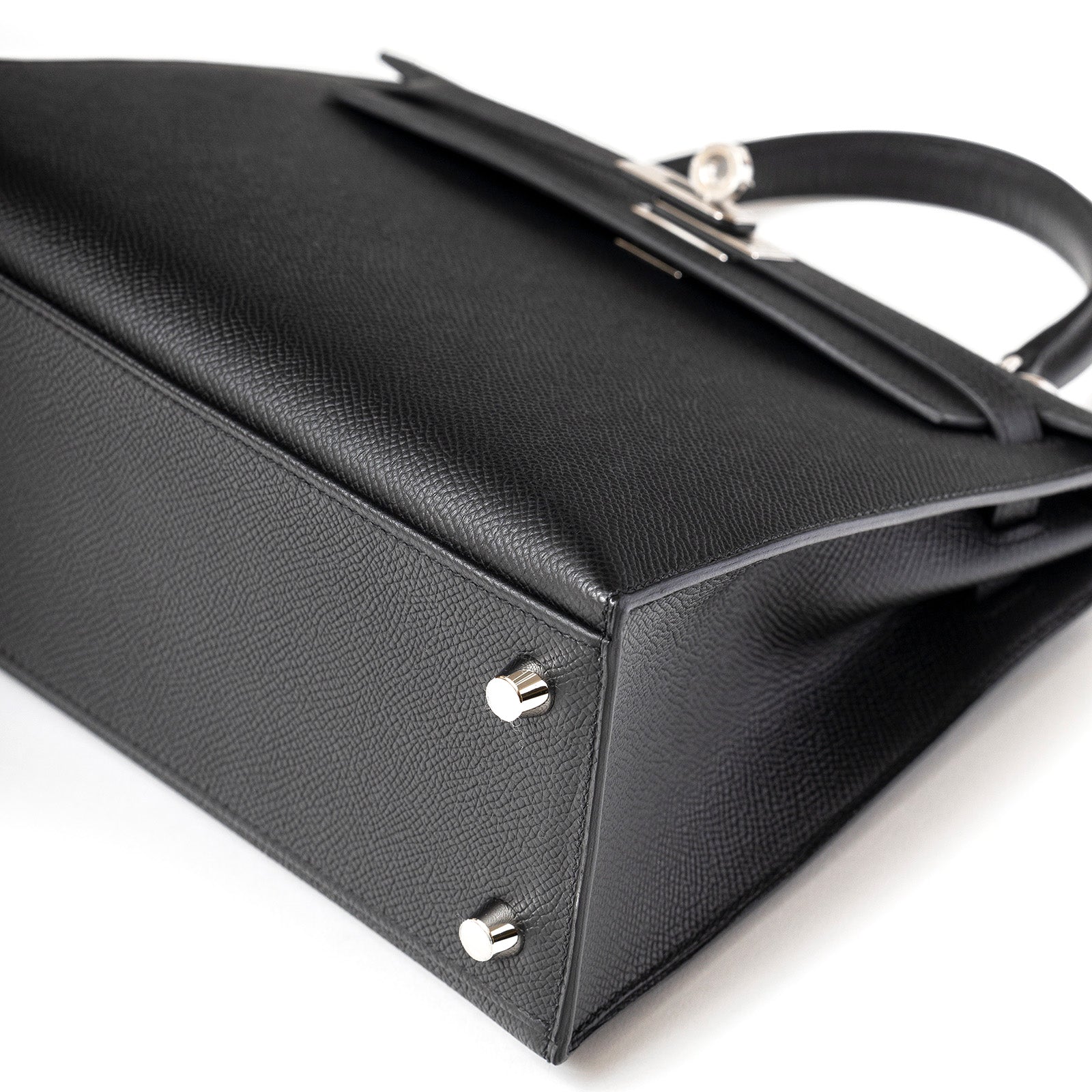 Close-up bottom view of Hermès Kelly 25 Sellier Black Epsom Palladium Hardware showing protective feet and texture