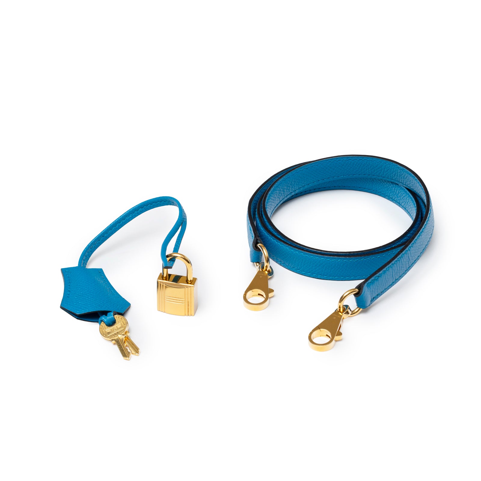 Close-up of Hermès Kelly Sellier 28 Blue Zanzibar Epsom Gold Hardware strap and lock with keys on white background