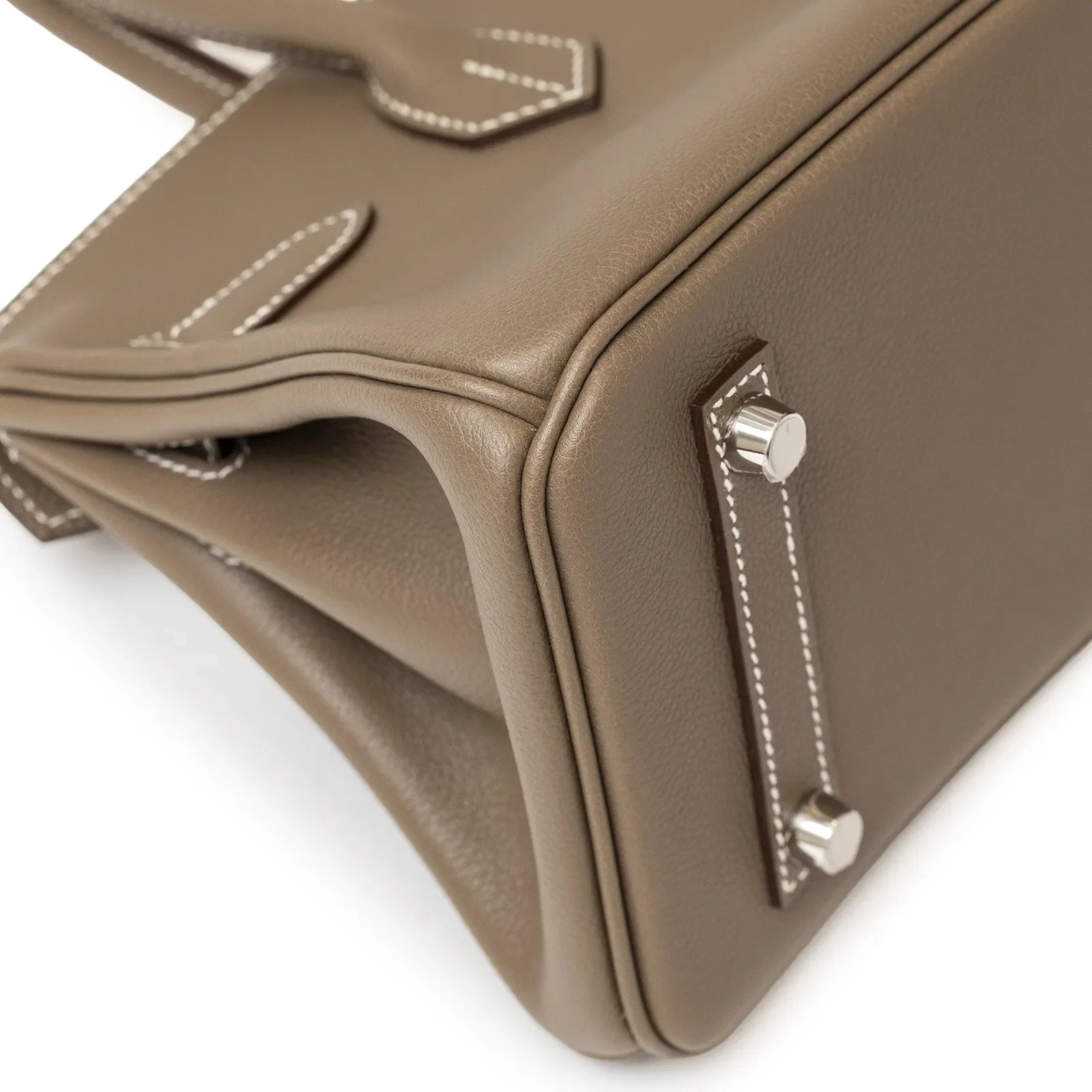 Close-up angled shot of Hermès Birkin 29 Etoupe leather corner with palladium feet and white stitching detail