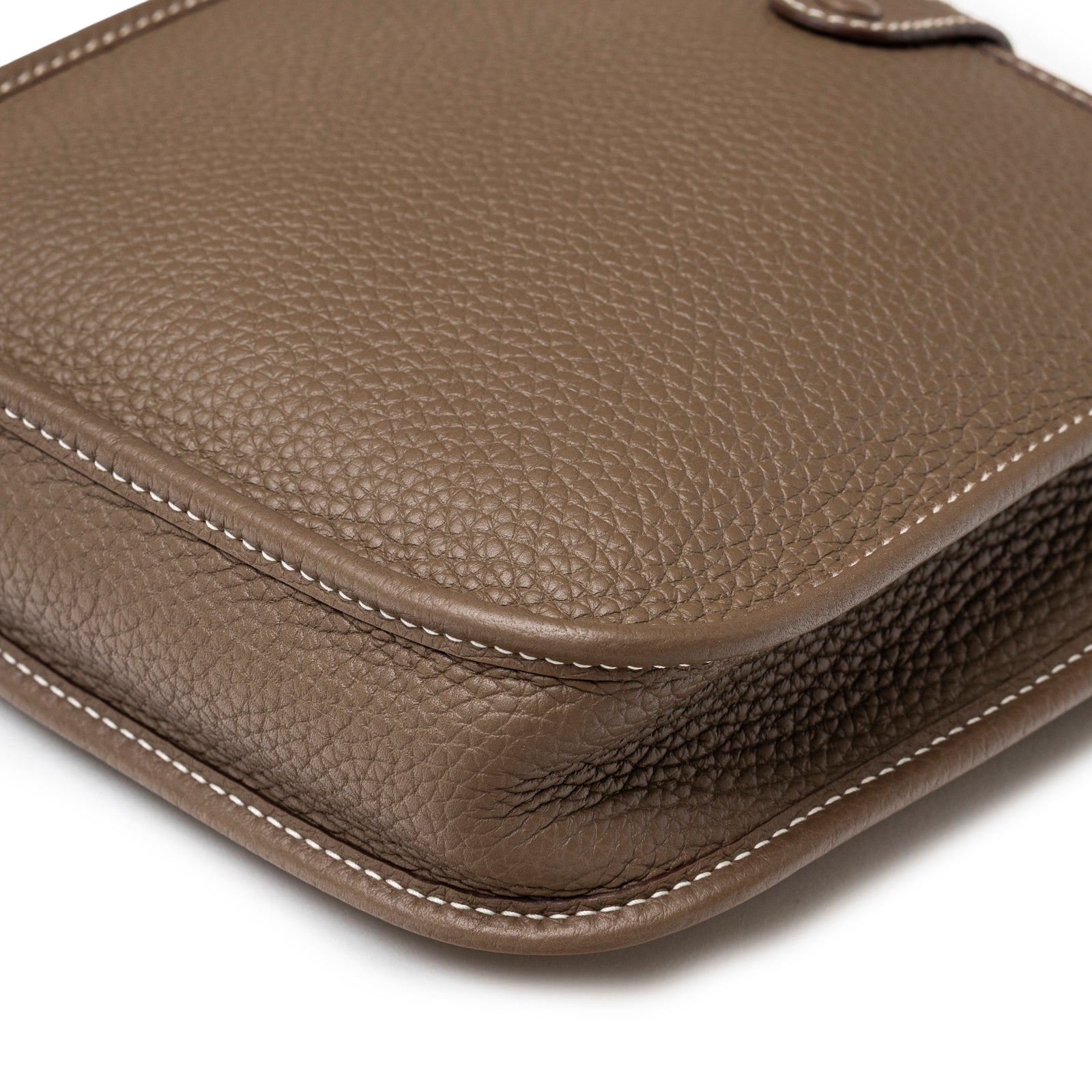 Close-up of corner and white stitching on Hermès Mini Evelyne Etoupe Blue Indigo Clemence Gold Hardware showing textured leather detail