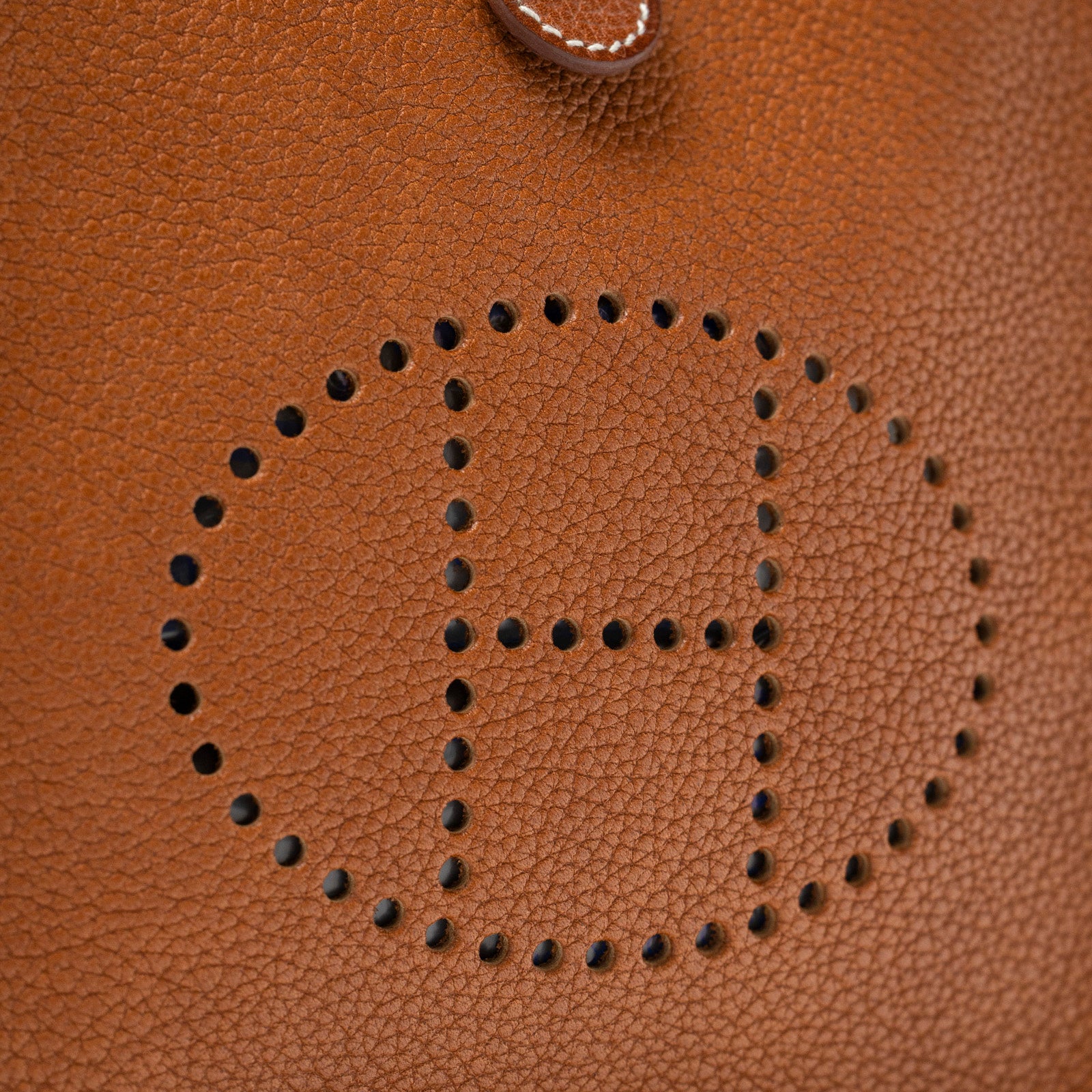 Close-up of perforated H logo detail on Hermès Mini Evelyne Fauve Barenia Palladium Hardware leather bag
