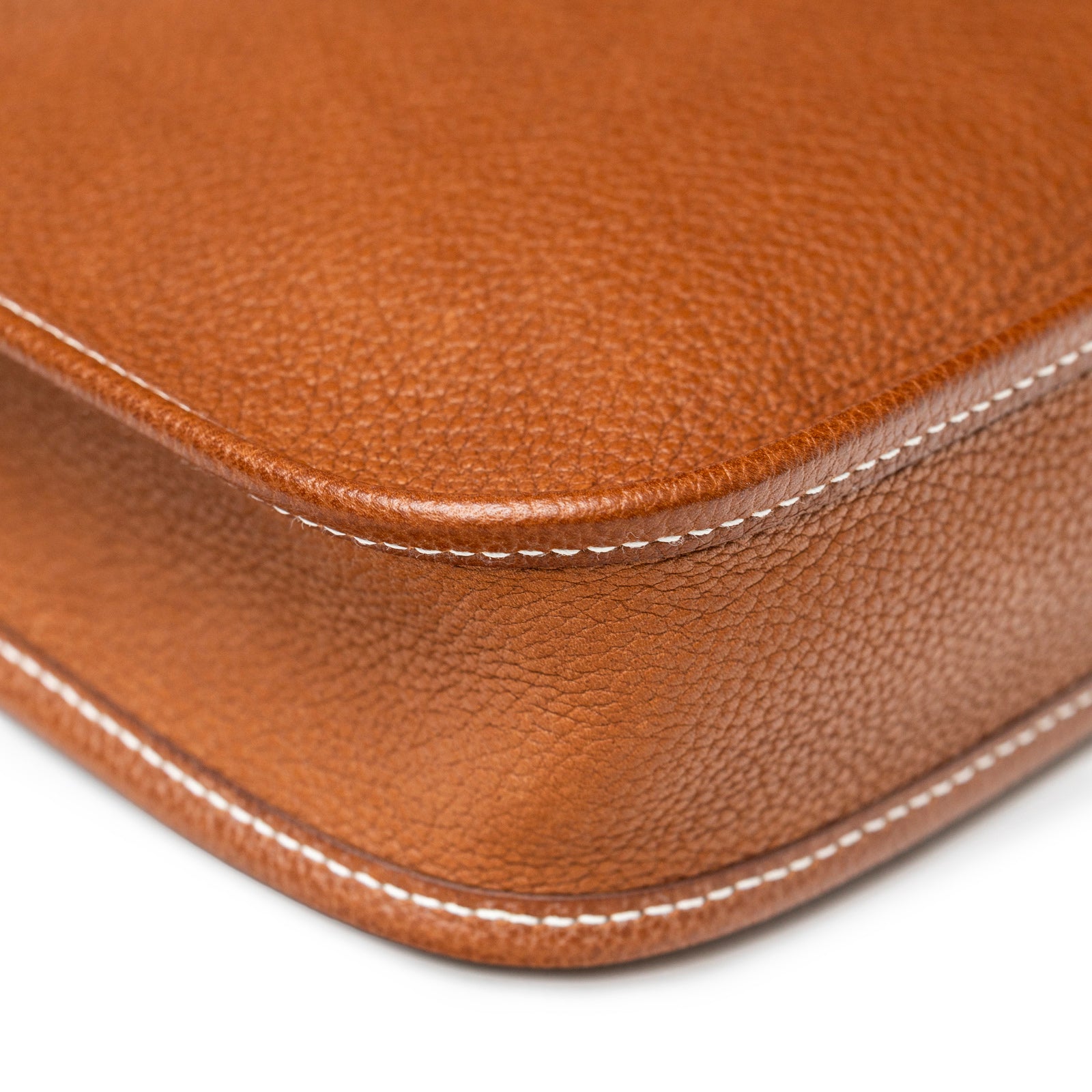 Close-up of Hermès Mini Evelyne Fauve Barenia Palladium Hardware corner showing textured leather and white stitching detail