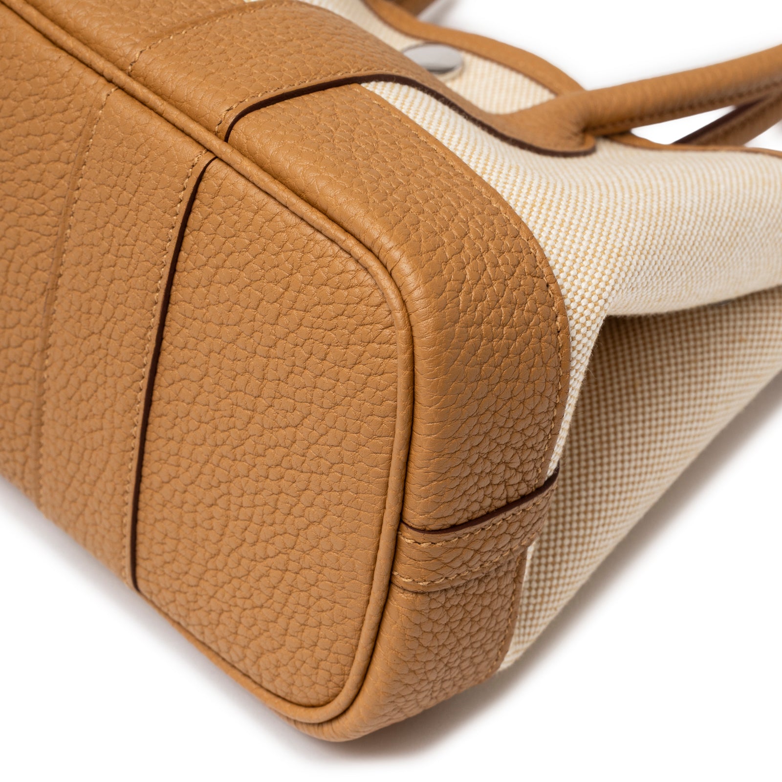 Close-up of bottom corner showing textured tan leather and Ecru-Paille Toile H Canvas on Hermès Mini Garden Party Neo 23 Ecru-Paille Toile H Canvas and Sesame Negonda Palladium Hardware