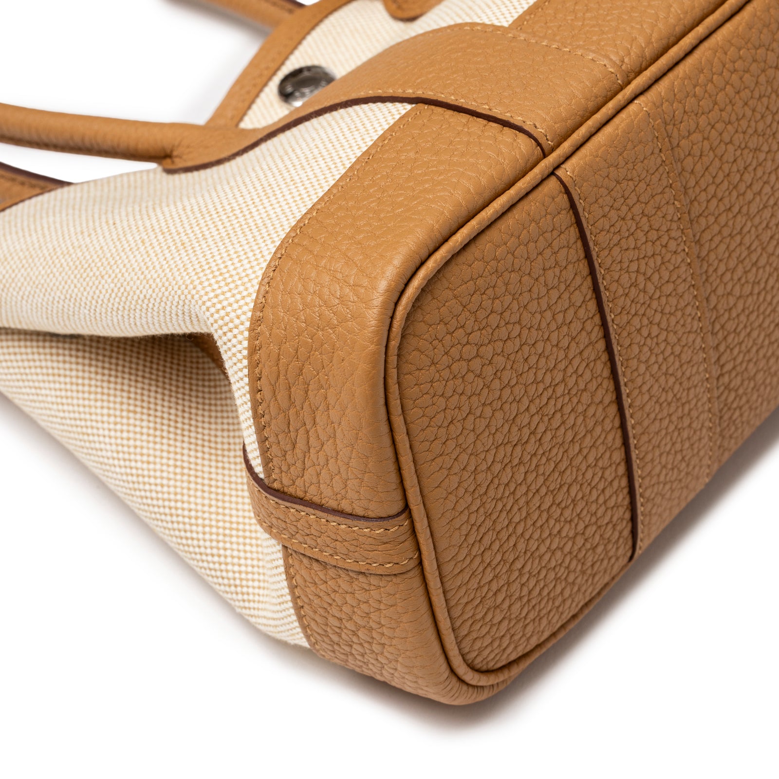 Close-up of bottom corner showing textured leather and canvas detail on Hermès Mini Garden Party Neo 23 Ecru-Paille Toile H Canvas and Sesame Negonda Palladium Hardware