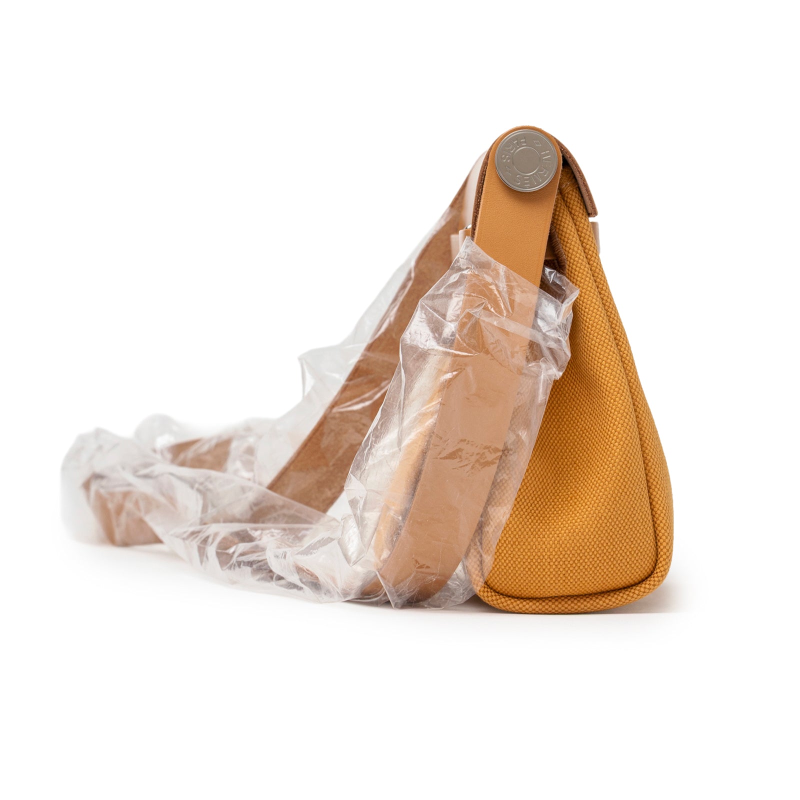 Side perspective of Hermès Mini Herbag Zip 20 Naturel Sable Toile and Vache Hunter Palladium Hardware showing canvas texture and leather strap wrapped in protective plastic