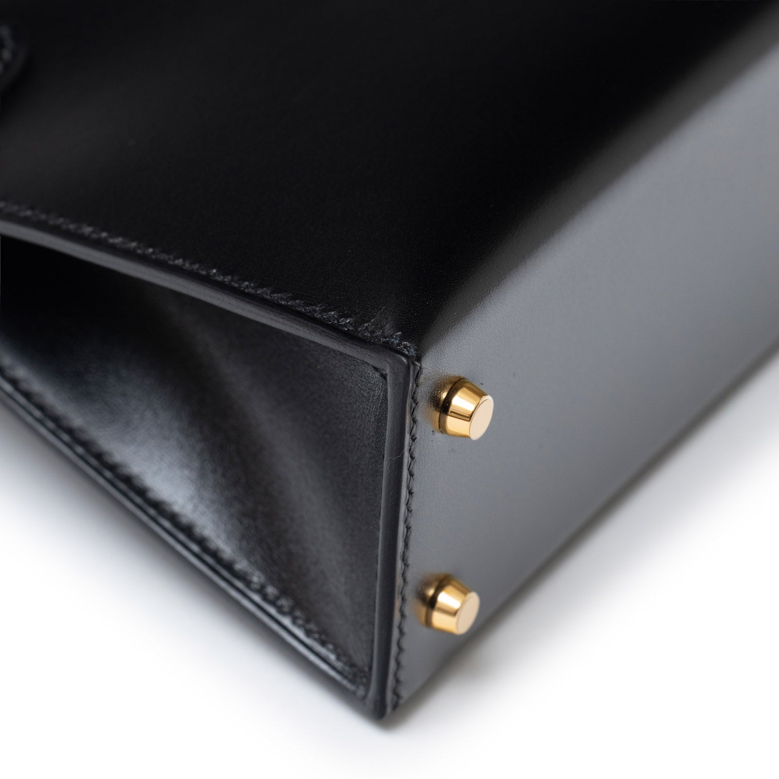 Close-up of the base with gold hardware feet on Hermès Mini Kelly II Sellier 20 Black Box Gold Hardware bag