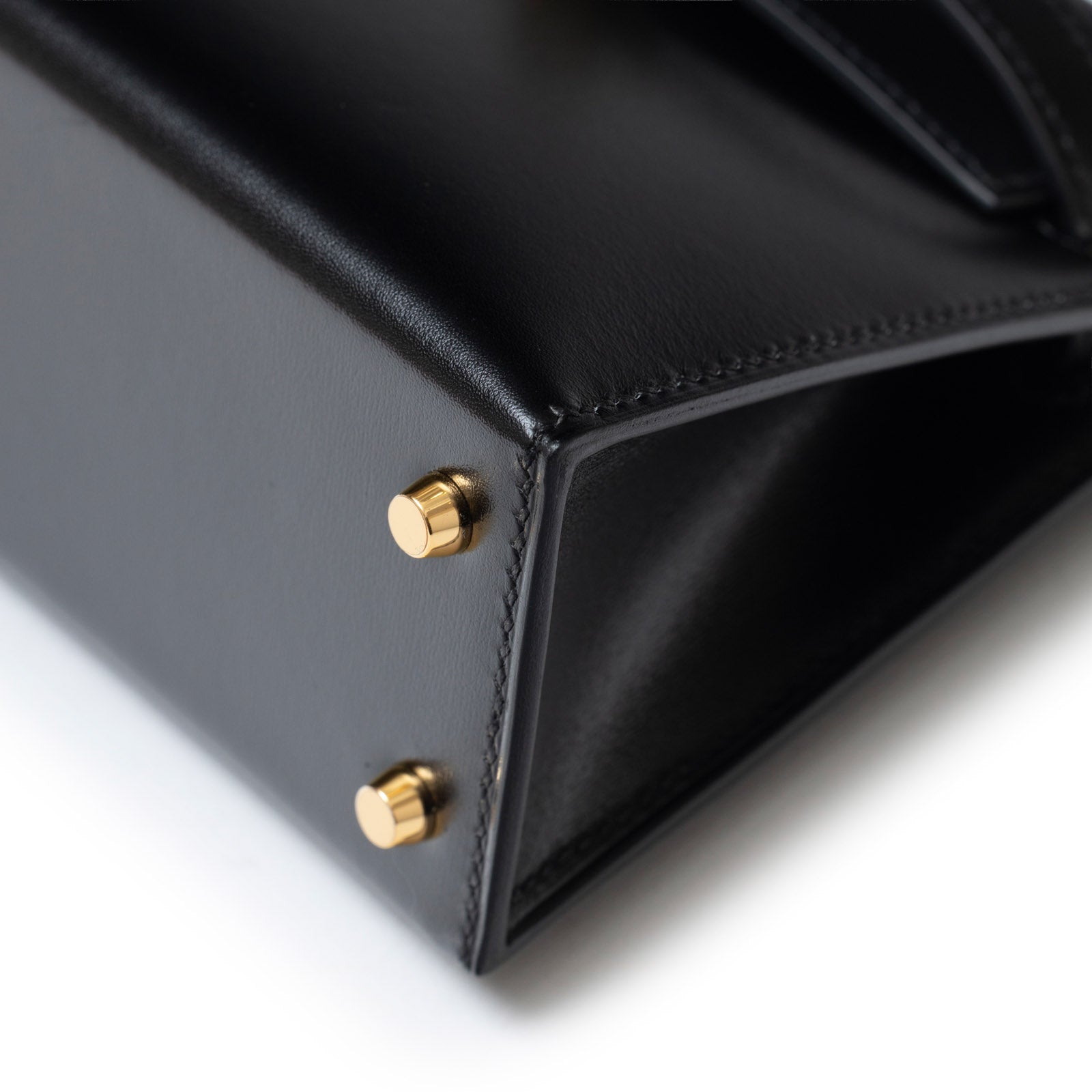 Close-up bottom corner view of Hermès Mini Kelly II Sellier 20 Black Box Gold Hardware showing stitching and feet detail
