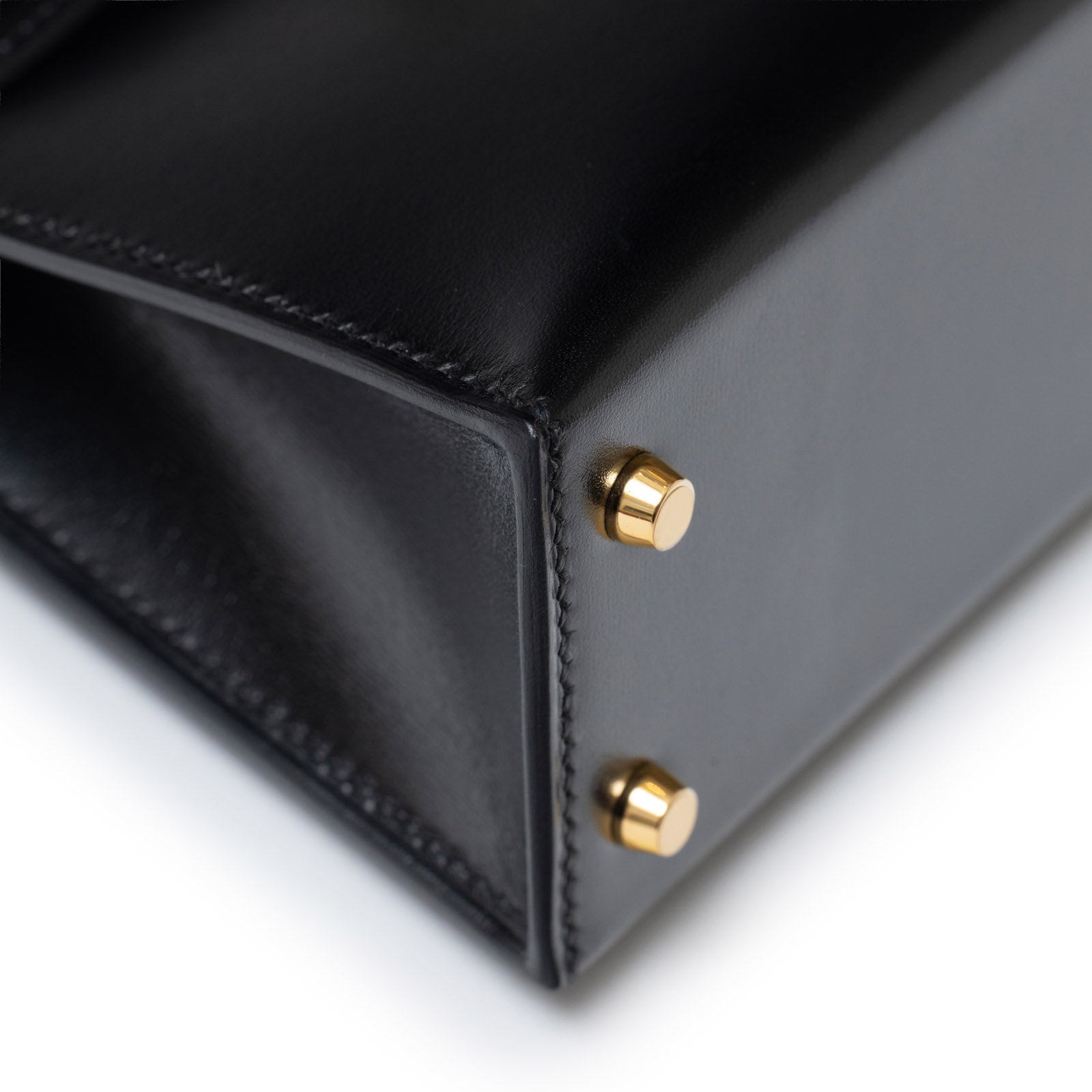 Close-up of Hermès Mini Kelly II Sellier 20 Black Box Gold Hardware showing gold feet and fine leather stitching detail