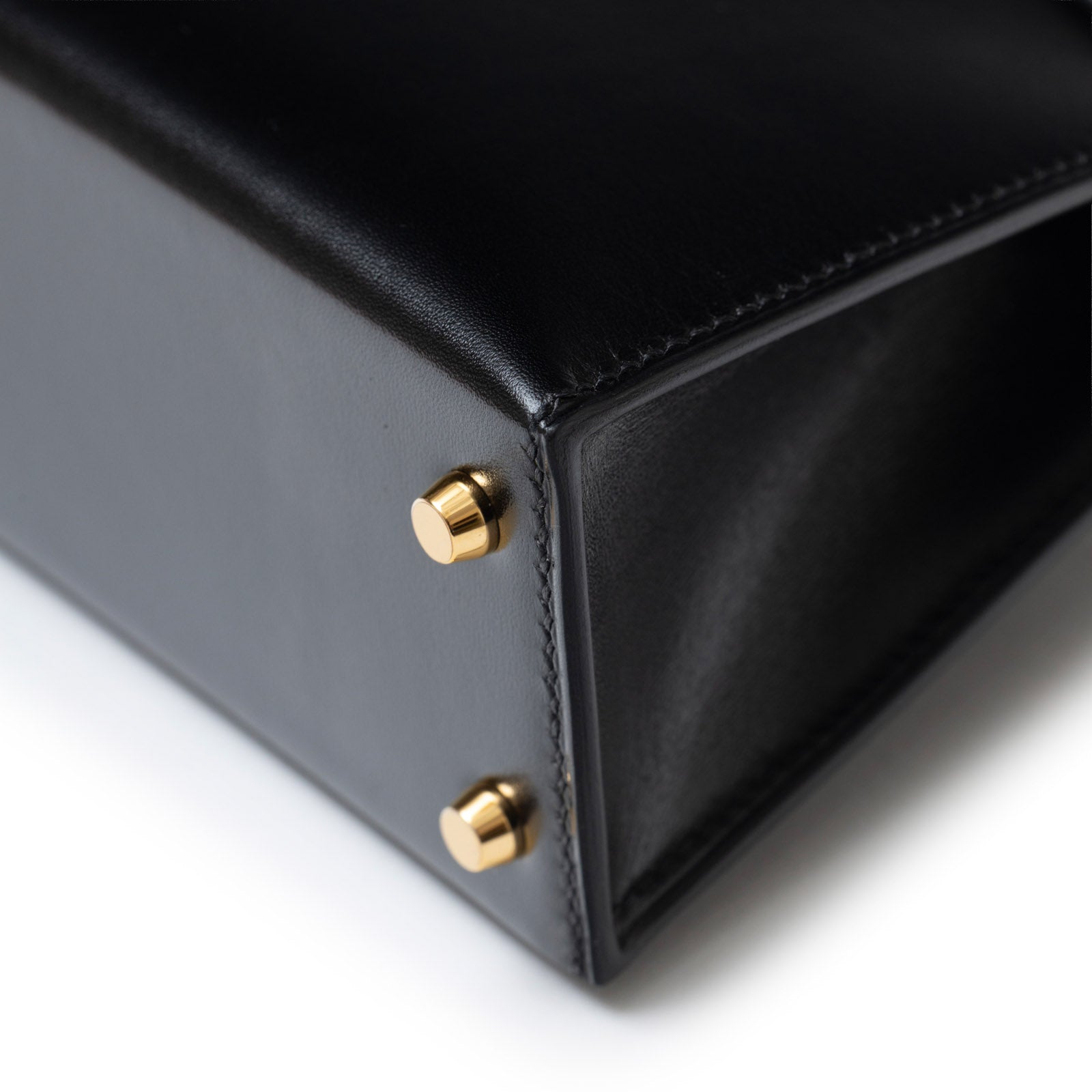 Close-up of base corner showing smooth leather and gold hardware feet on Hermès Mini Kelly II Sellier 20 Black Box Gold Hardware