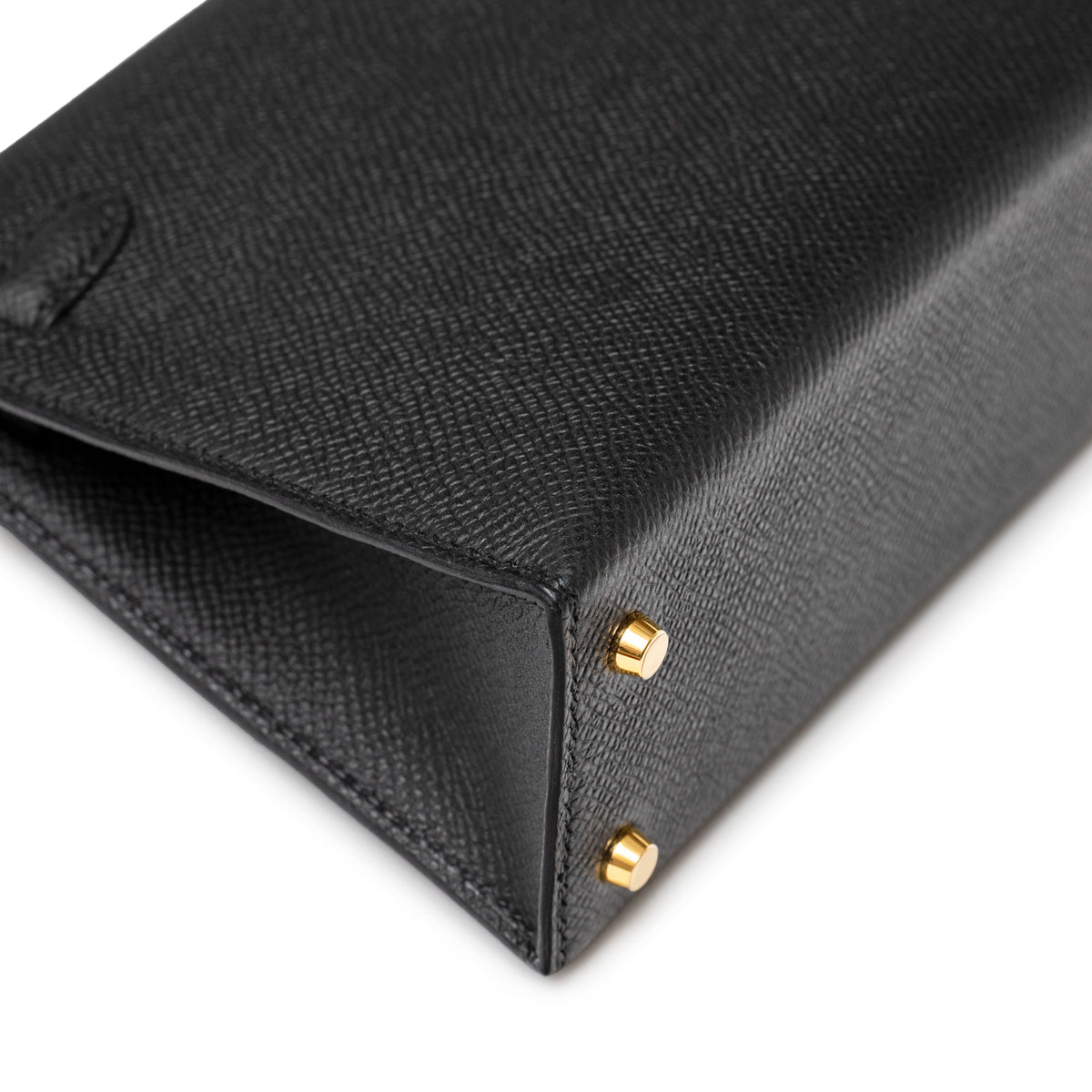 Close-up of corner and base showing black textured leather and gold hardware feet on Hermès Mini Kelly II Sellier 20 Black Epsom Gold Hardware