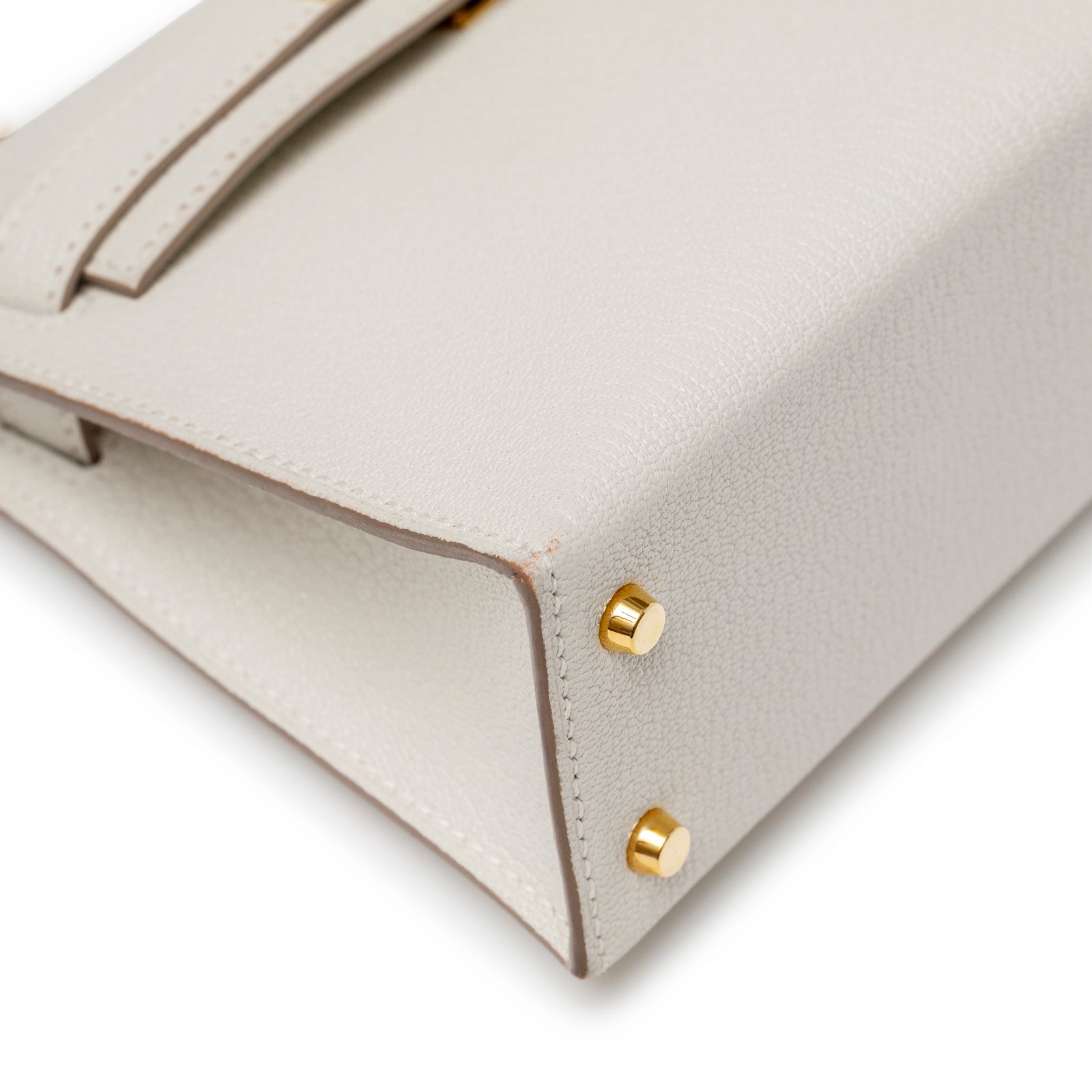 Close-up of base corner on Hermès Mini Kelly II Sellier Mushroom Chevre Mysore Gold Hardware showing leather grain and gold studs detail