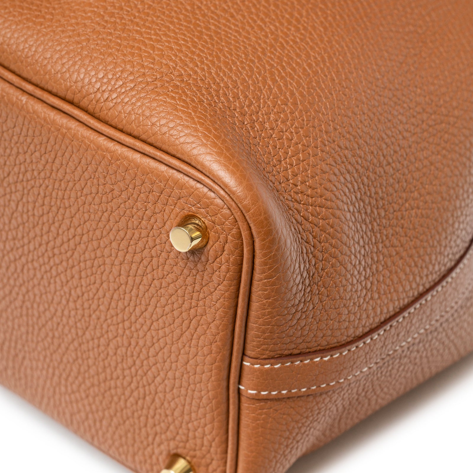 Close-up of textured leather and gold feet hardware at bottom corner of Hermès Picotin 18 Gold Clemence Gold Hardware