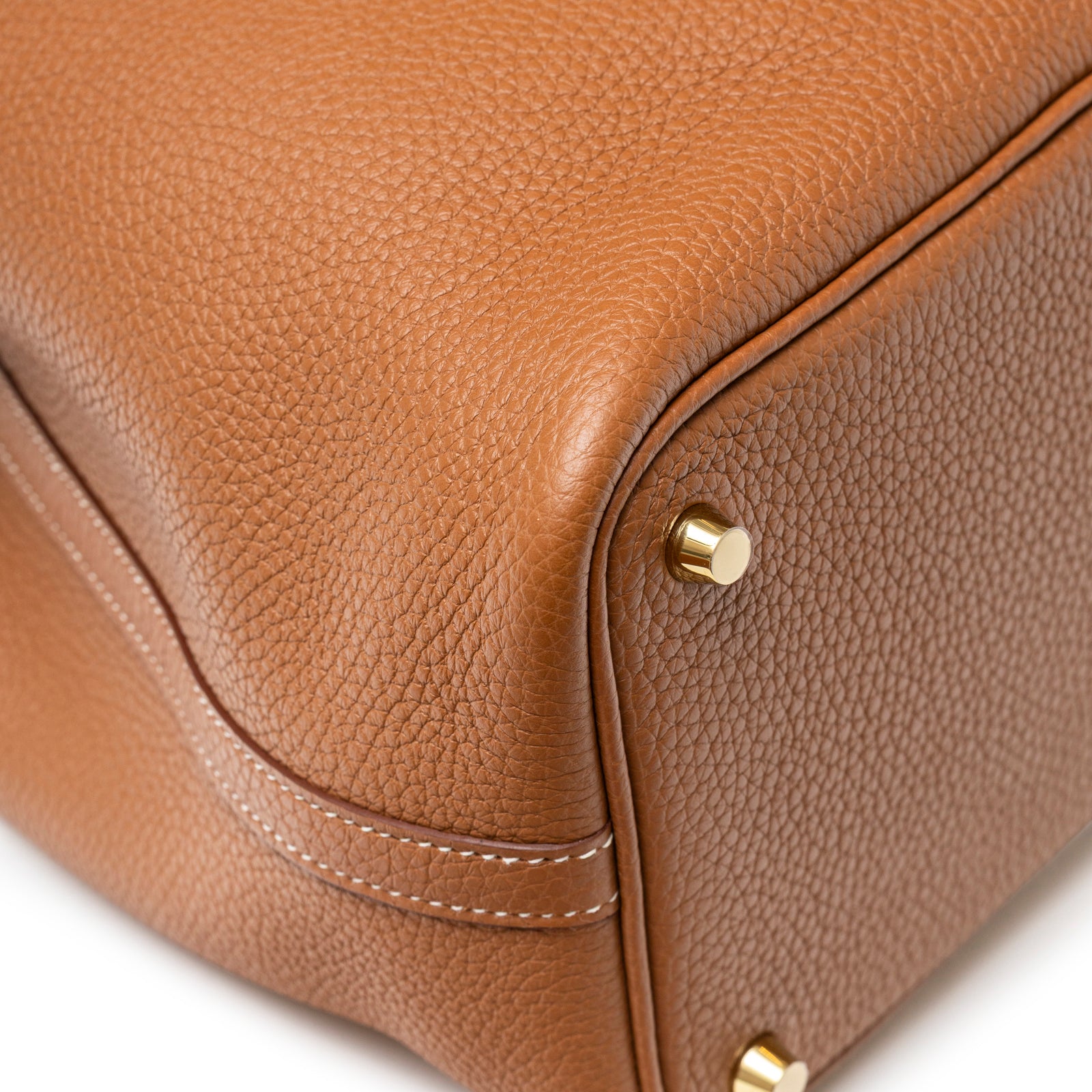 Close-up of bottom corner showing rich brown textured leather and polished gold feet on Hermès Picotin 18 Gold Clemence Gold Hardware