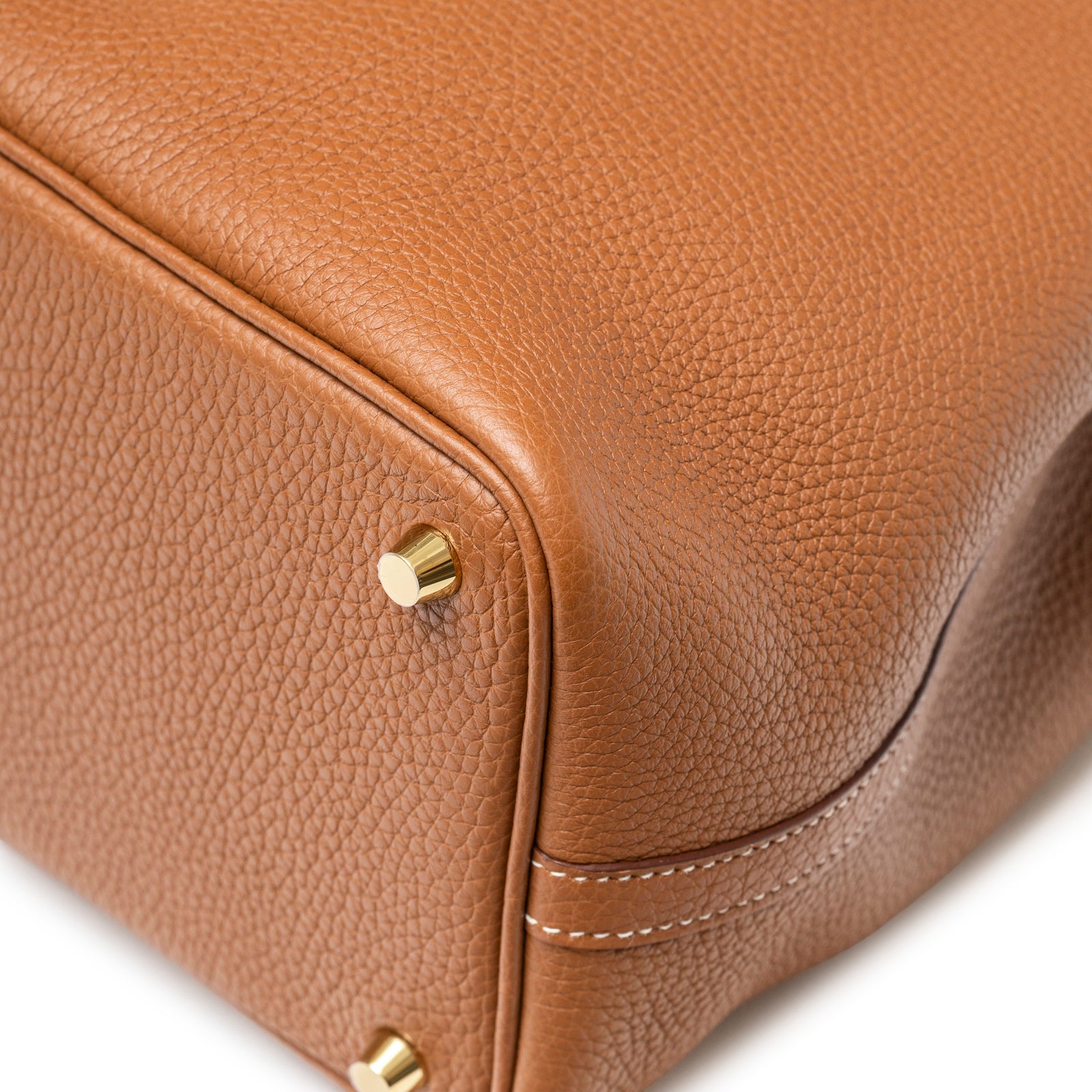 Close-up of rich tan Clemence leather grain and gold hardware feet on Hermès Picotin 18 Gold Clemence Gold Hardware