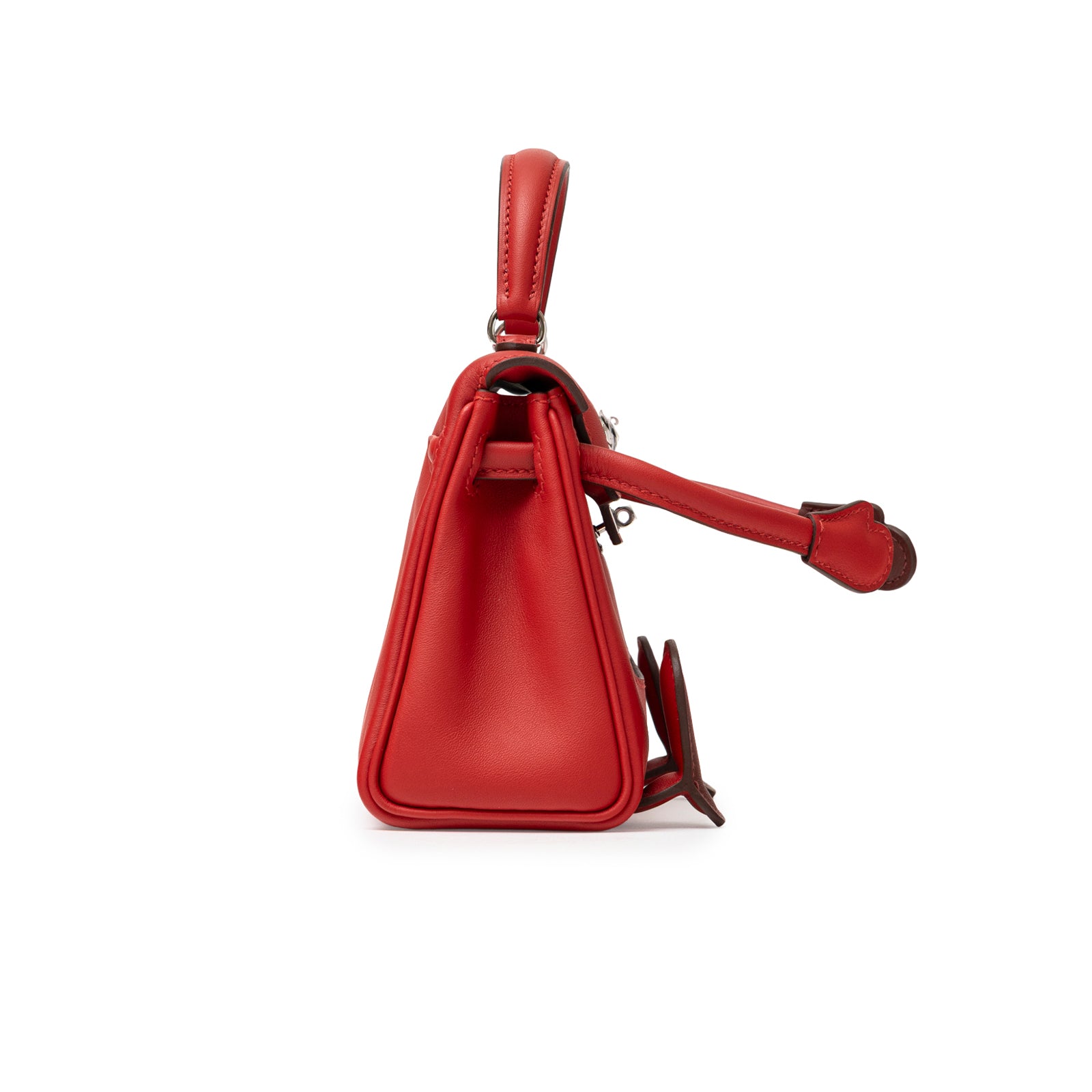 Side view of Hermès Quelle Idolle Kelly Doll Rouge Radieux Rouge H Swift Palladium Hardware bag showing structured silhouette and handle.