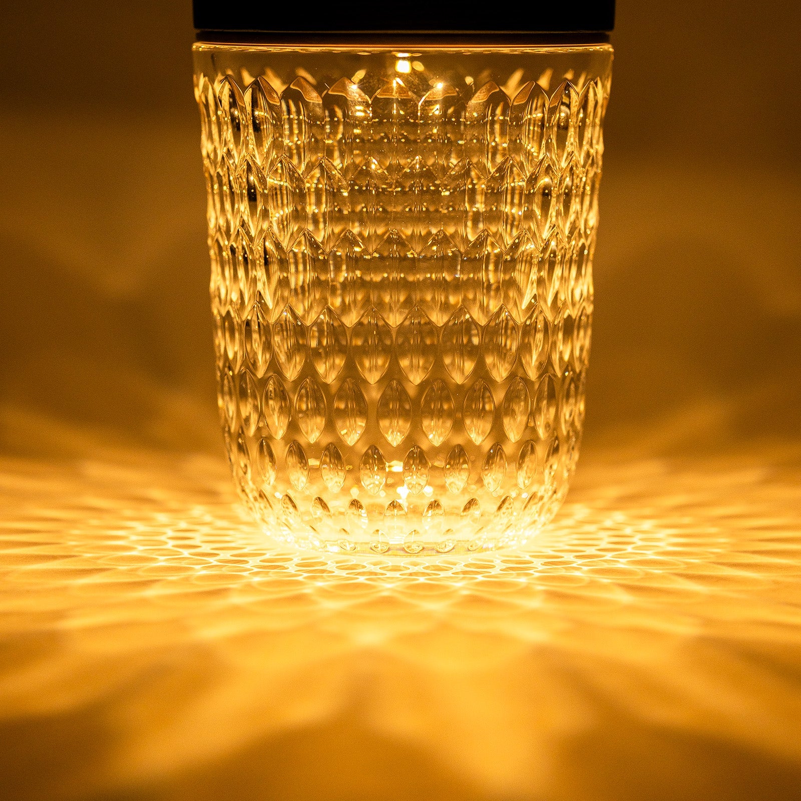 Close-up front view of Hermès Saint Louis Folia Baladeuse Light Clair Clear/ Dark Wood glowing with textured glass light pattern.
