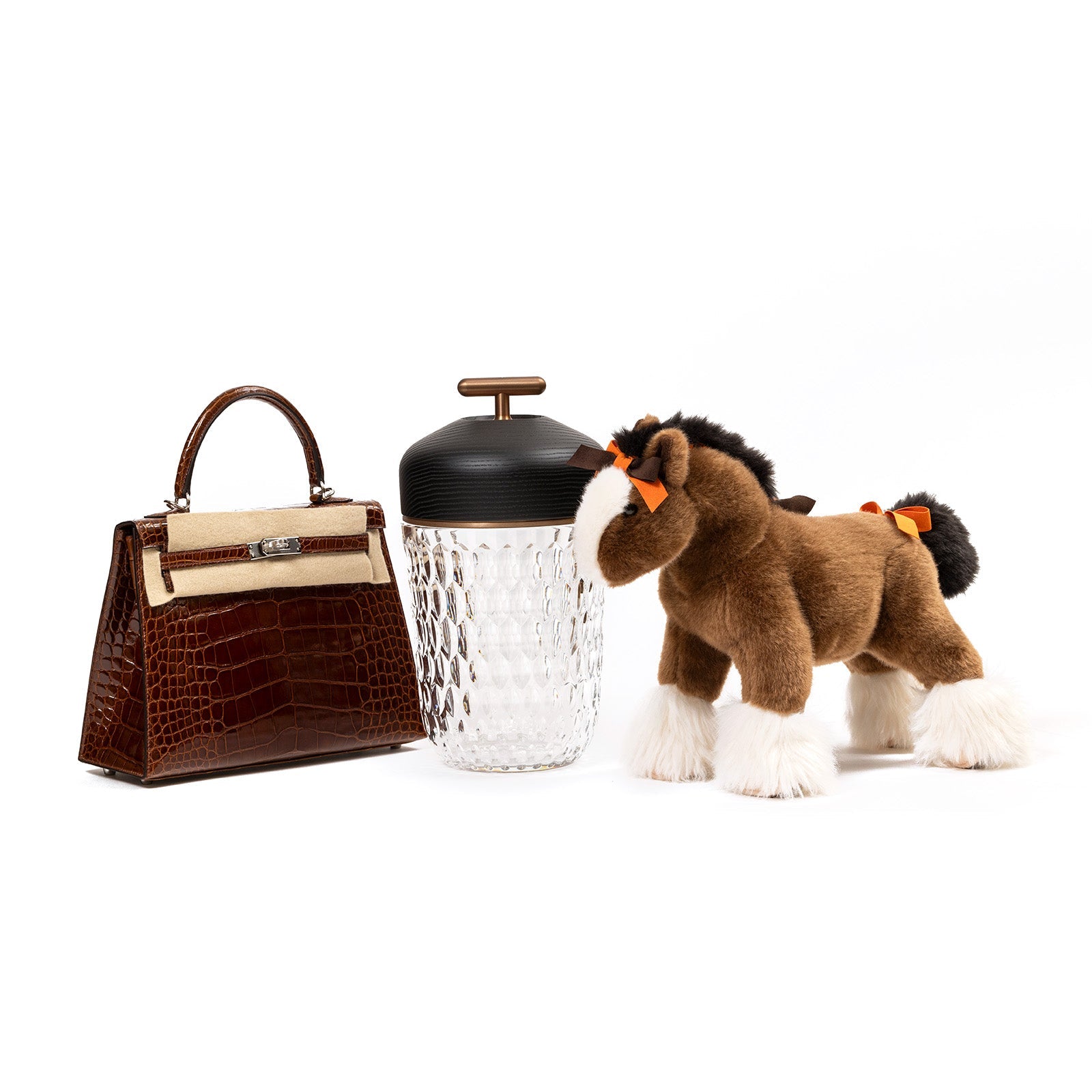 Angled view of Hermès Saint Louis Folia Baladeuse Light Clair Clear/ Dark Wood decorative glass container with brown horse and leather handbag
