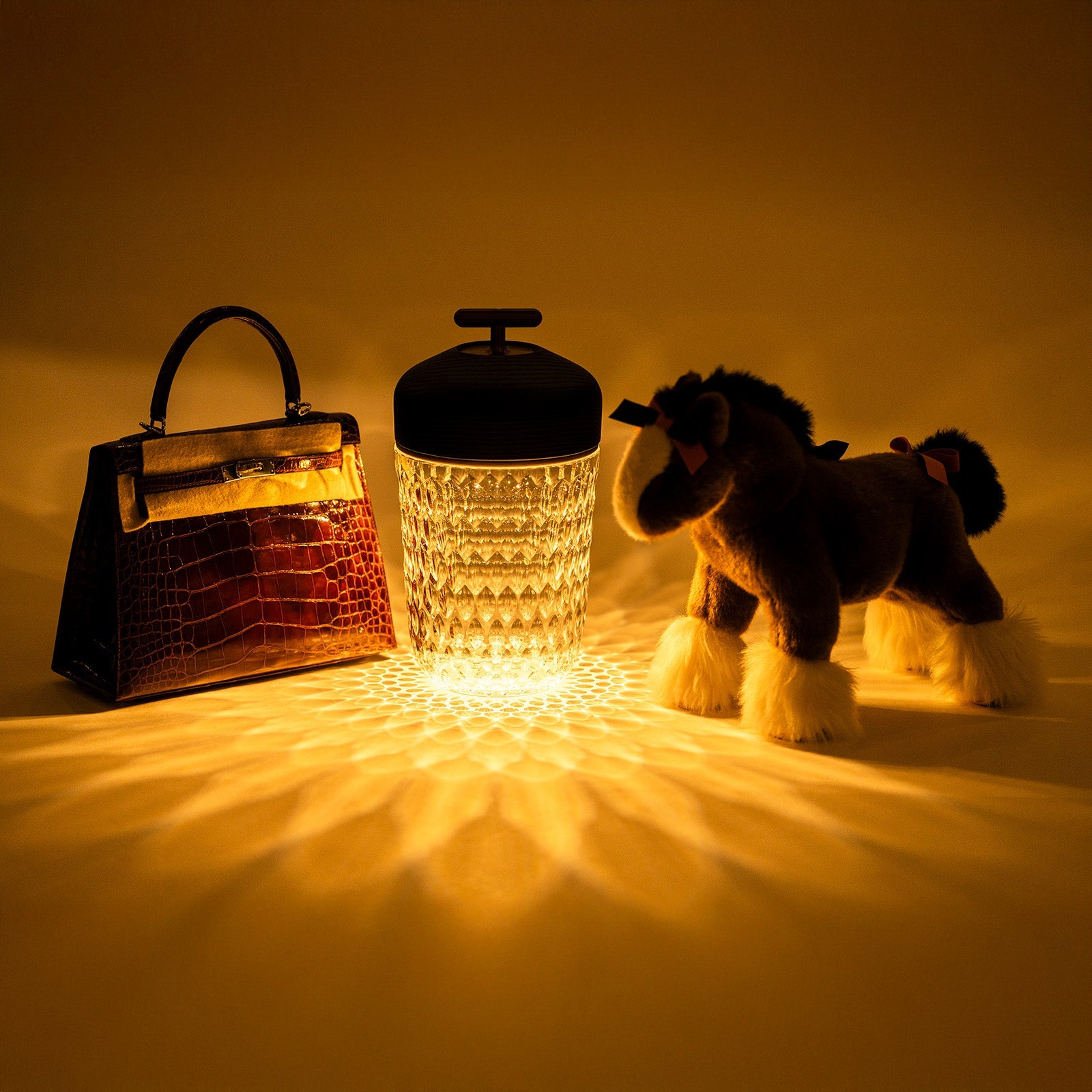 Angled shot of Hermès Saint Louis Folia Baladeuse Light Clair Clear/ Dark Wood lamp glowing with textured light patterns