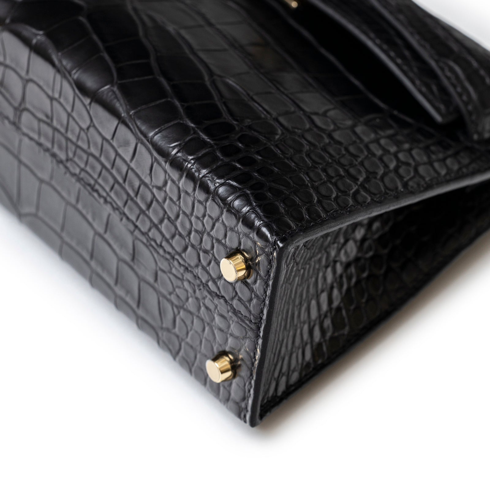 Close-up of Hermès Special Order HSS Horseshoe Mini Kelly II Black Blue Matte Alligator Permabrass Hardware base with matte alligator texture and permabrass feet