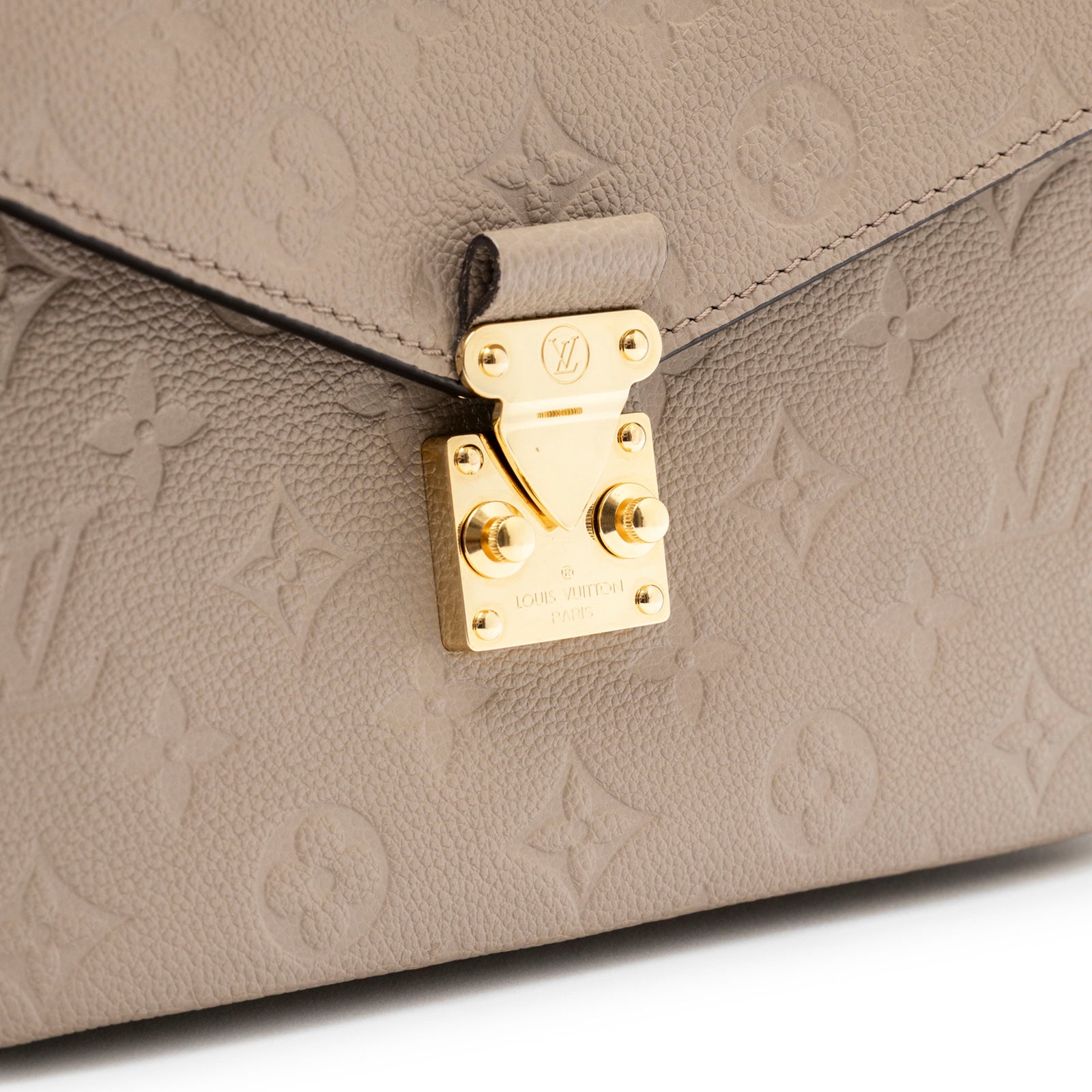 Close-up of gold hardware clasp and monogram embossing on Louis Vuitton Pochette Métis Monogram Empreinte Turtledove Gold Hardware