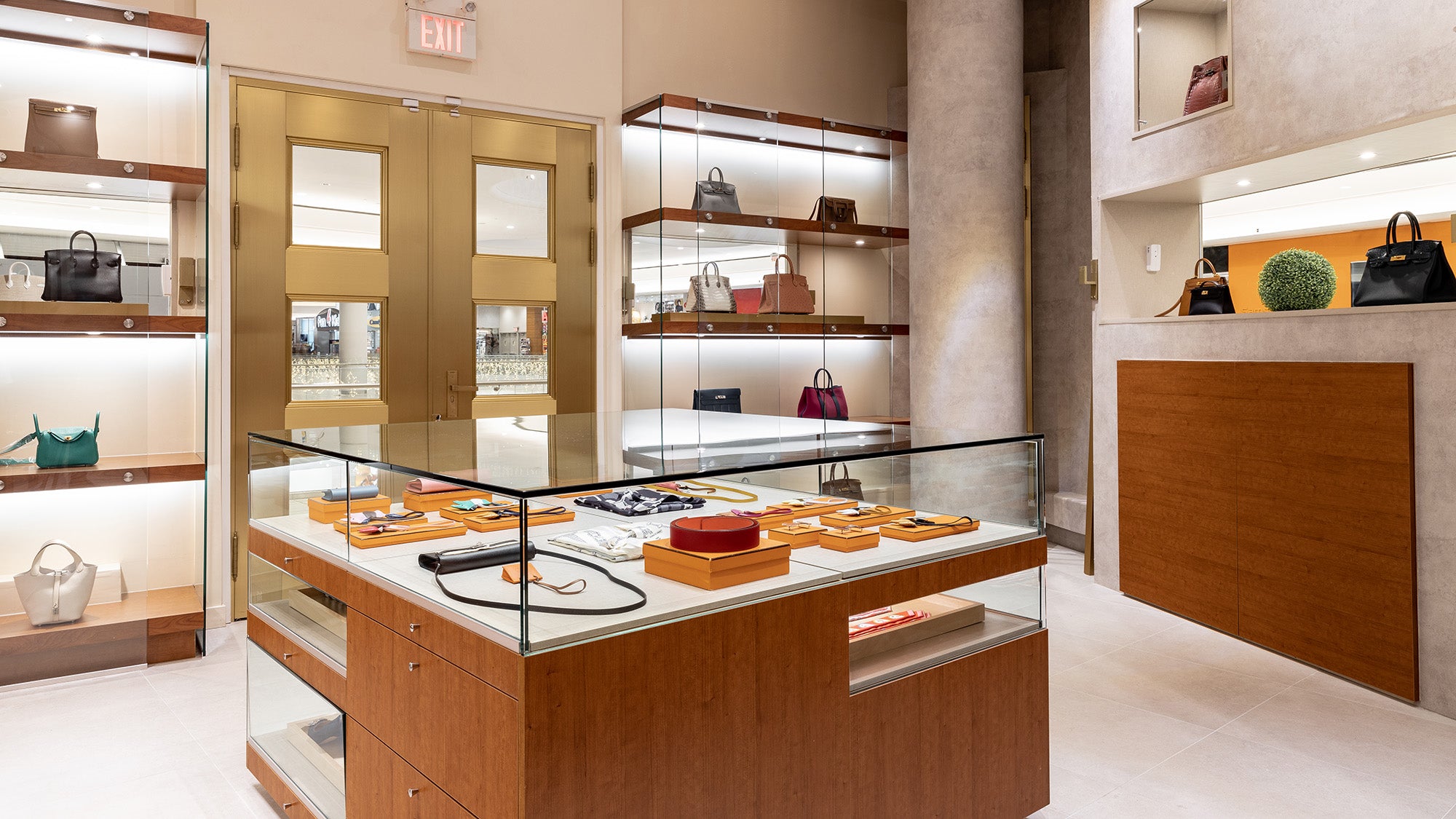 Luxury handbag boutique interior with glass display cases, shelving, and wooden counters