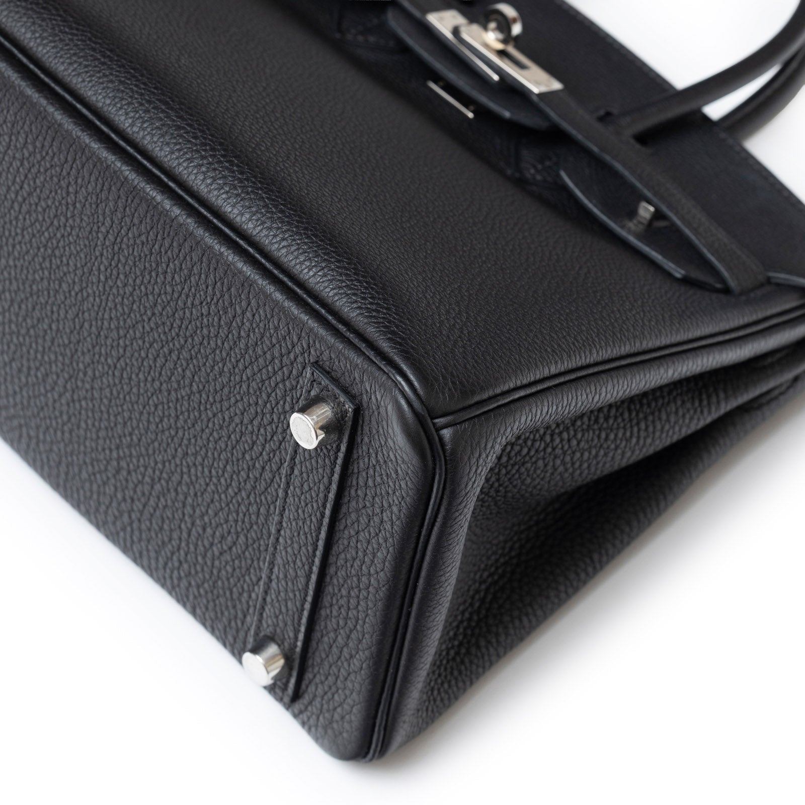 Close-up angled view of Hermès Birkin 25 Black Togo Palladium Hardware showing textured leather and metal feet details
